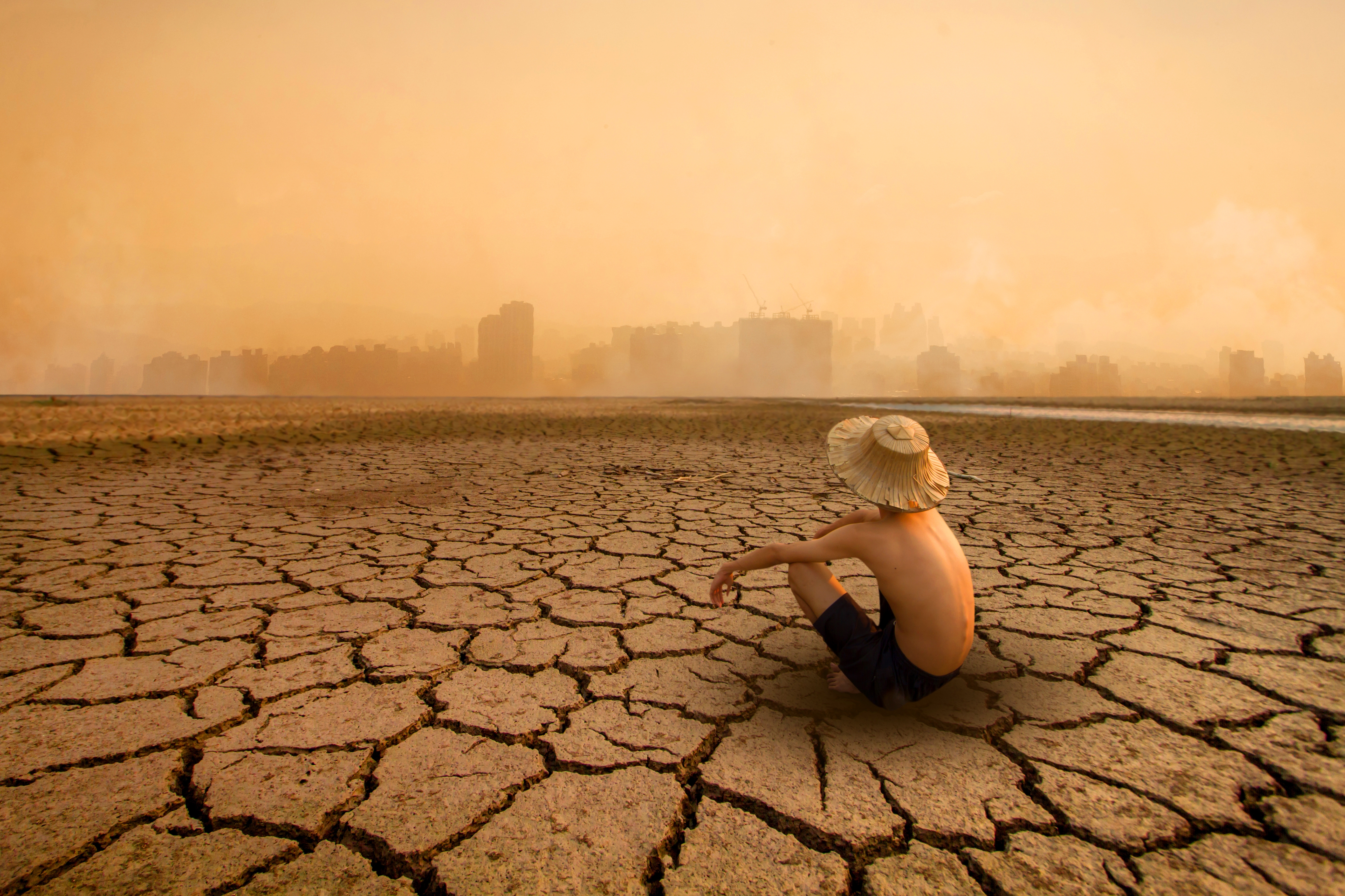 Young,Man,Sitting,On,Drying,River,And,Looking,To,Polluted