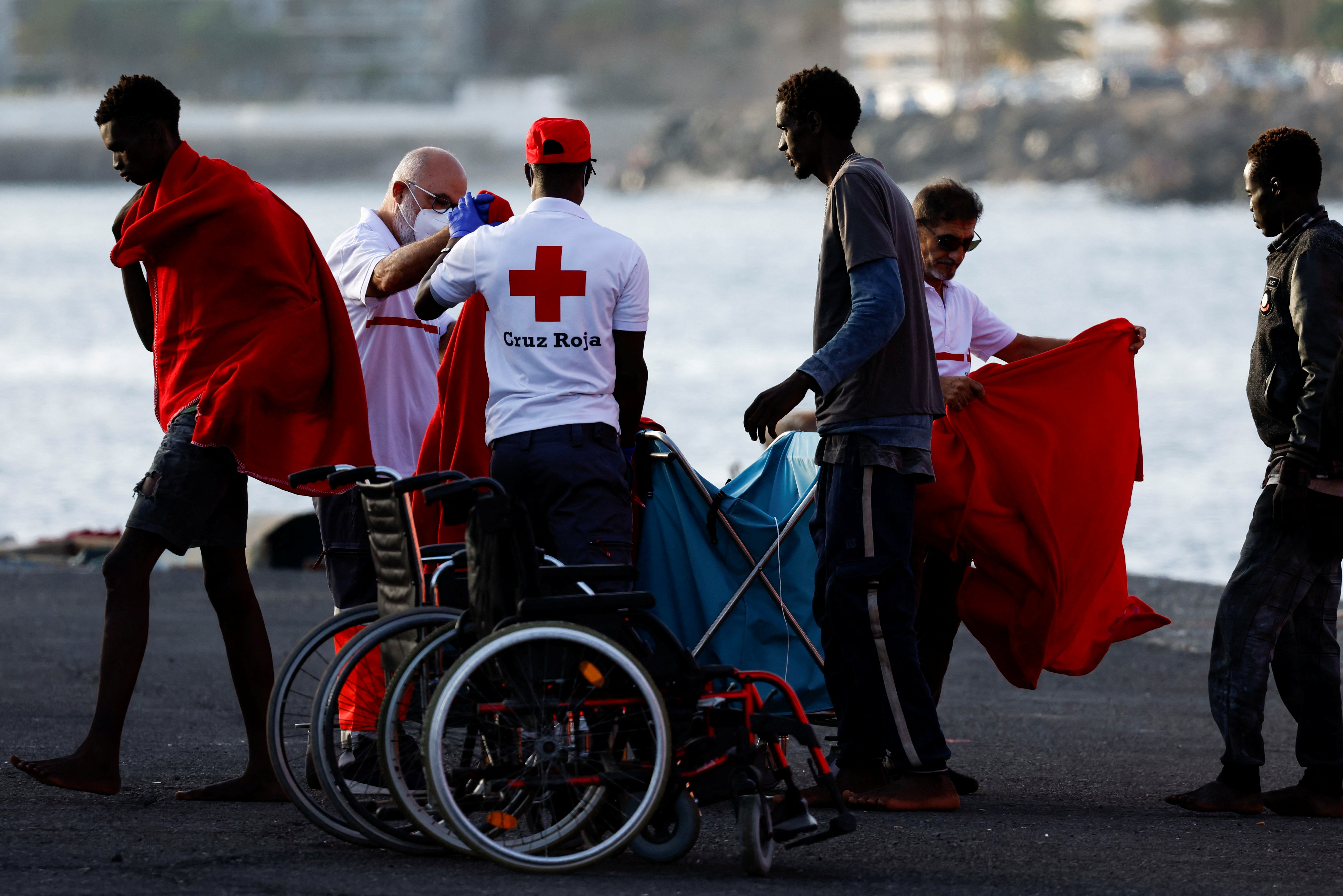 Migrants walk towards a Red Cross tent after disembarking from a Spanish coast guard vessel in the port of Arguineguin