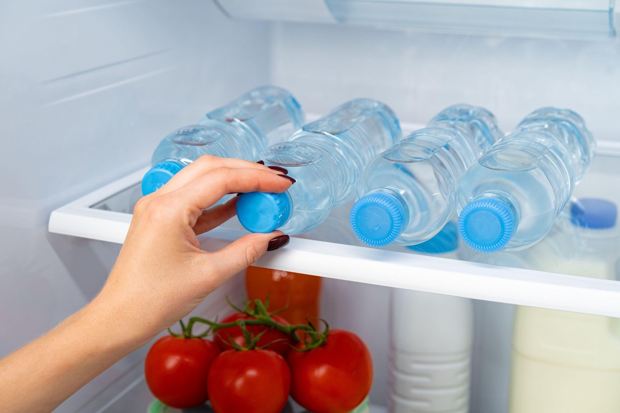 Female hand taking bottle of water from a fridge