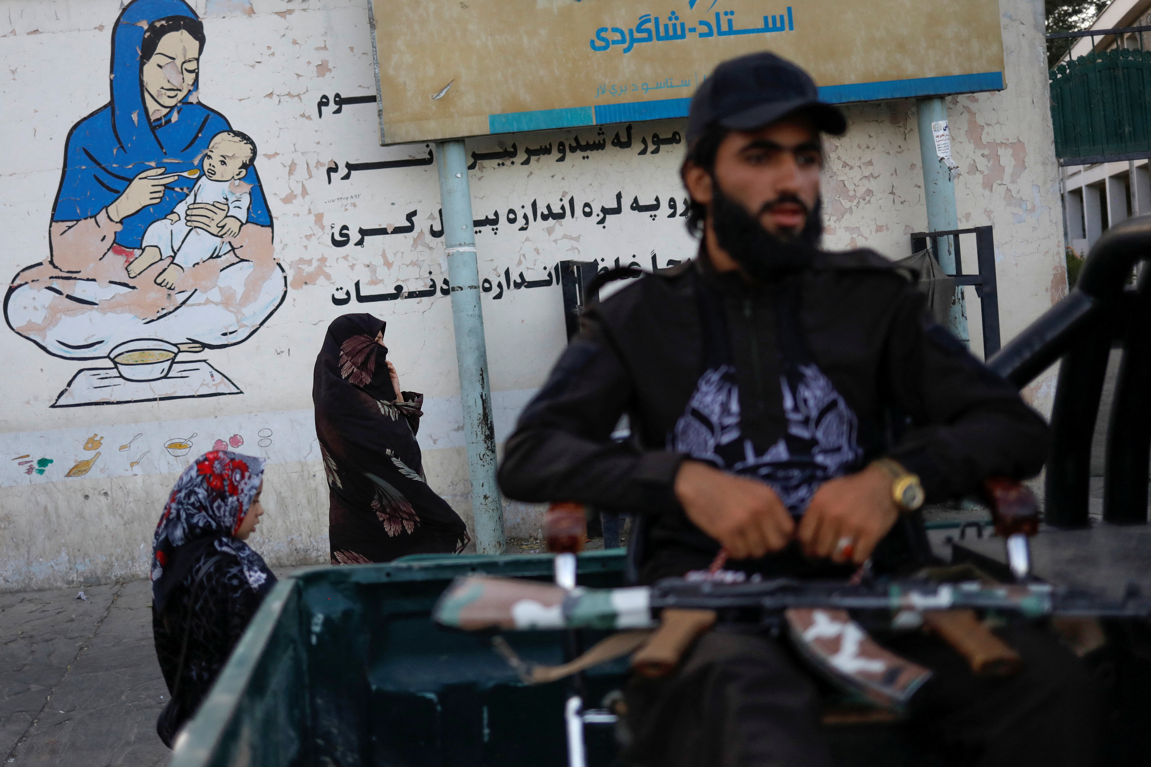An Afghan woman and a girl walk in a street in Kabul