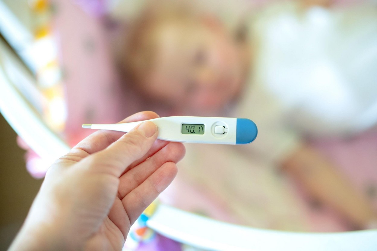 Close-up medical thermometer, Parent measuring temperature of ill kid, 1 years old toddler girl gets high fever lying on bed. fever in child.