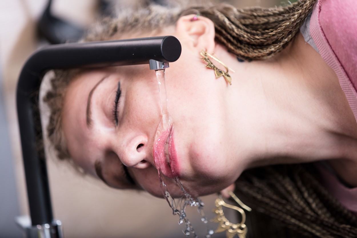 Attractive woman drinking water from a tap