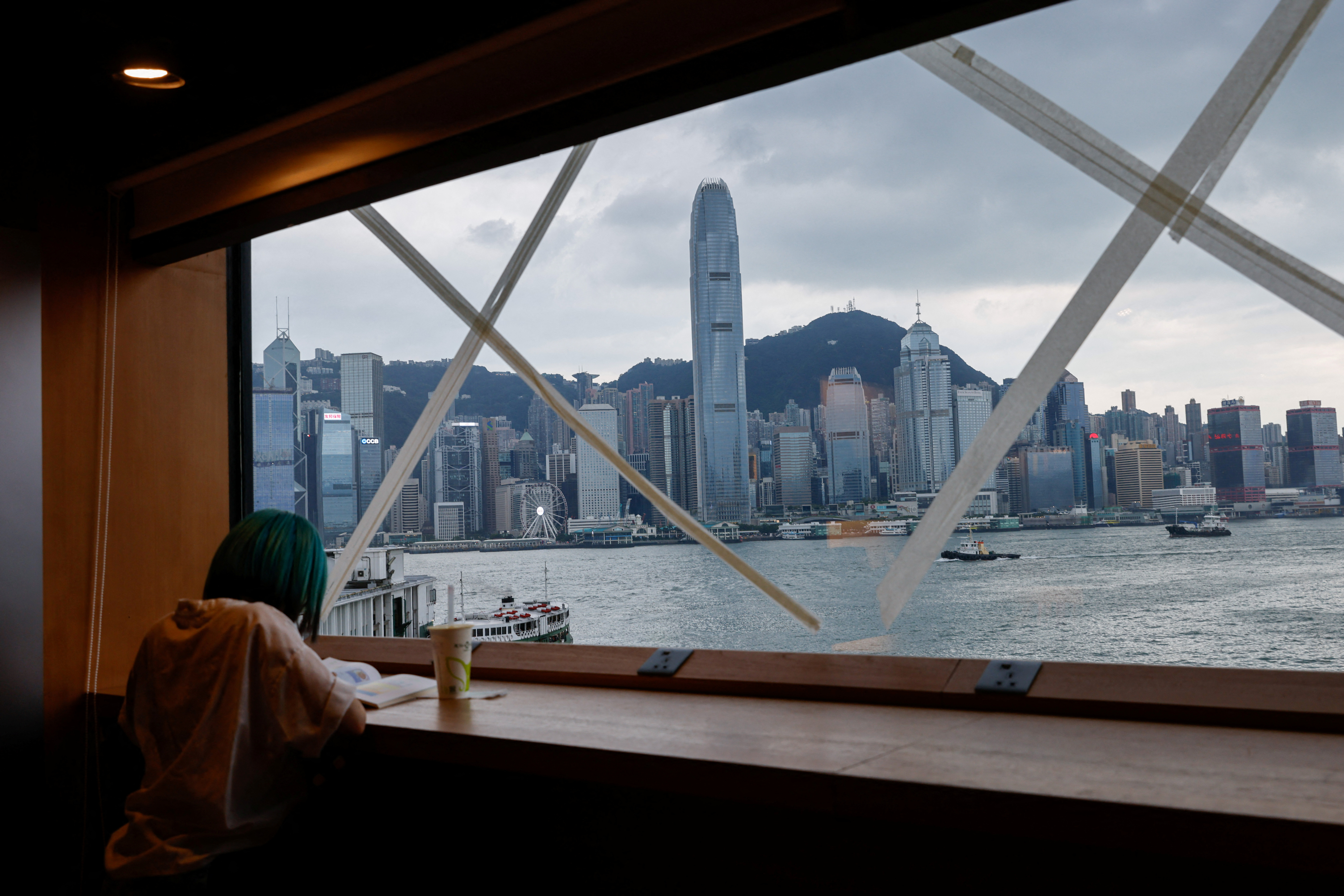 A girl reads a book at a bookstore, which windows are taped in anticipation of typhoon Saola in Hong Kong