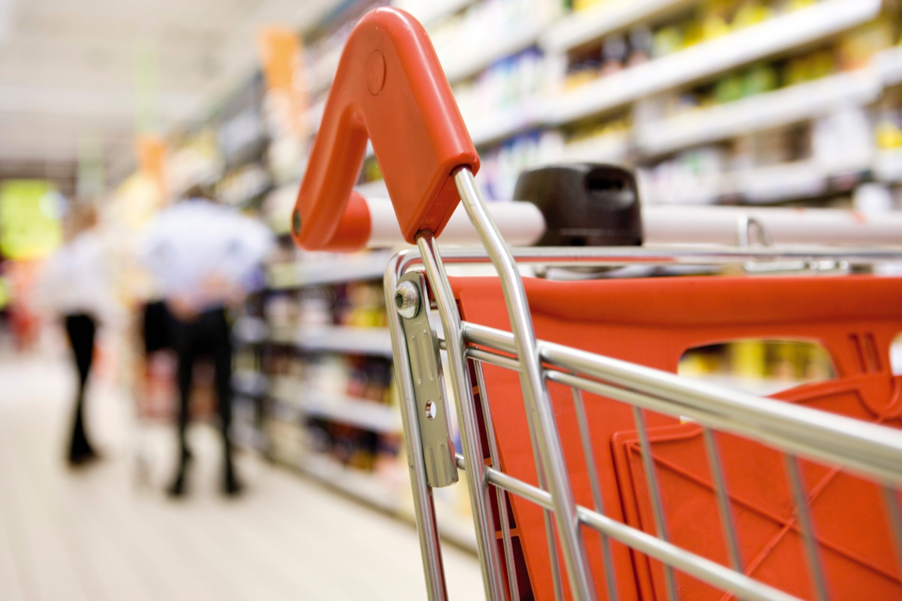 Shopping cart in supermarket, shoppers in background