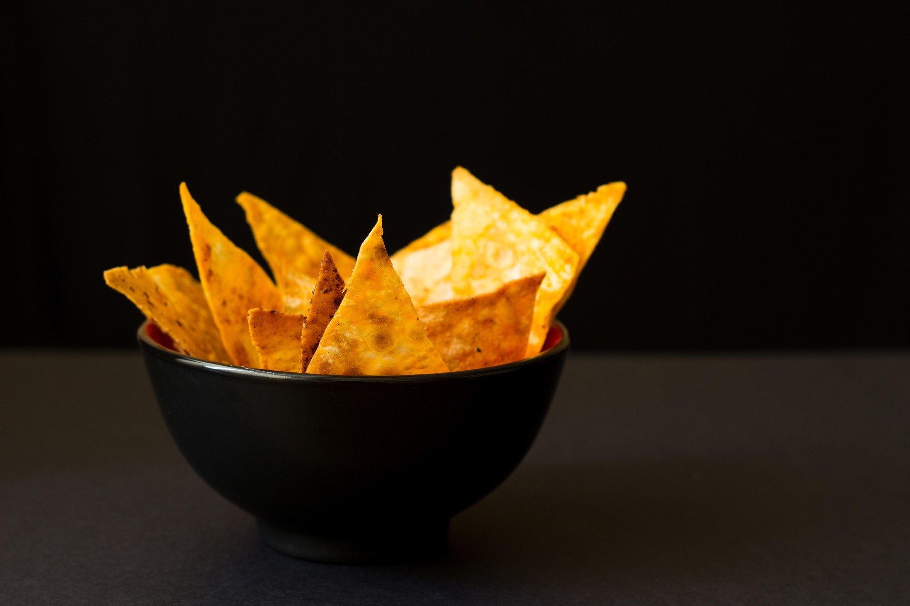 Fried spicy Mexican tortilla chips in black bowl