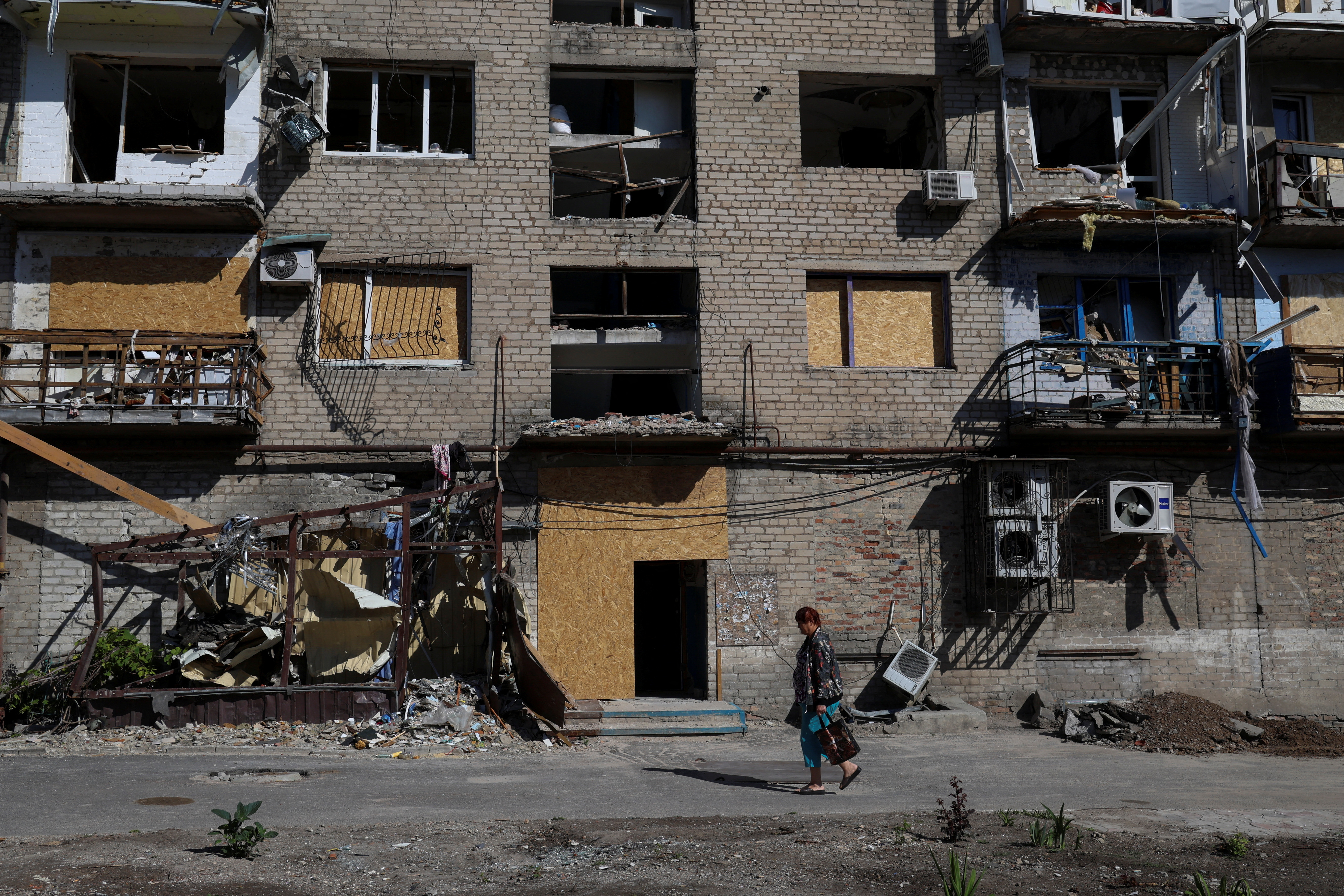 Woman walks past a residential building damaged by a Russian military strike in Pokrovsk