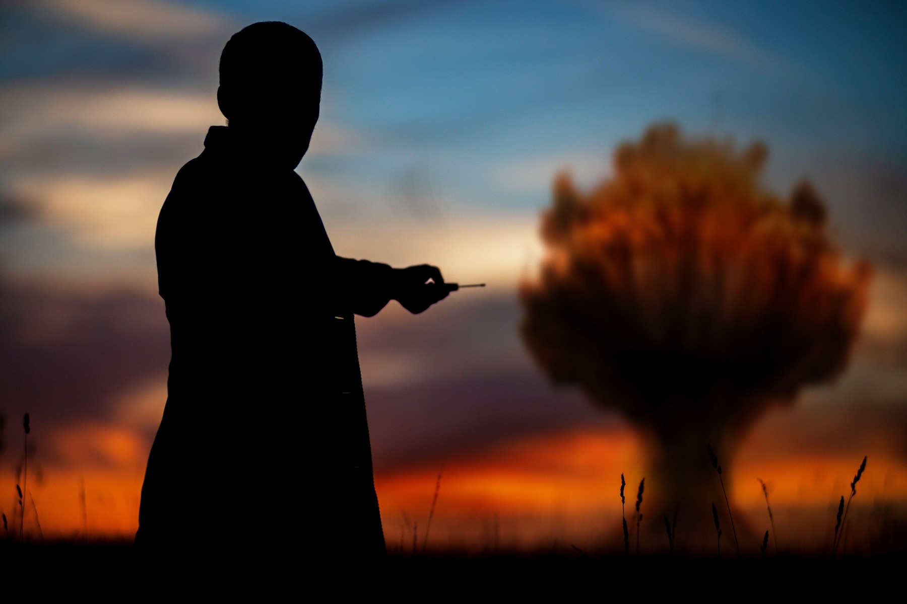 The concept of a nuclear strike. Silhouette of a man with a remote control in his hands making an explosion. A politician who started a nuclear war