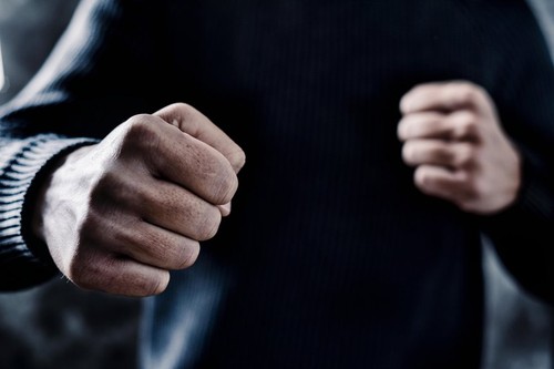closeup of a young caucasian man in casual wear with a threatening gesture, ready to punch or fight with his fists