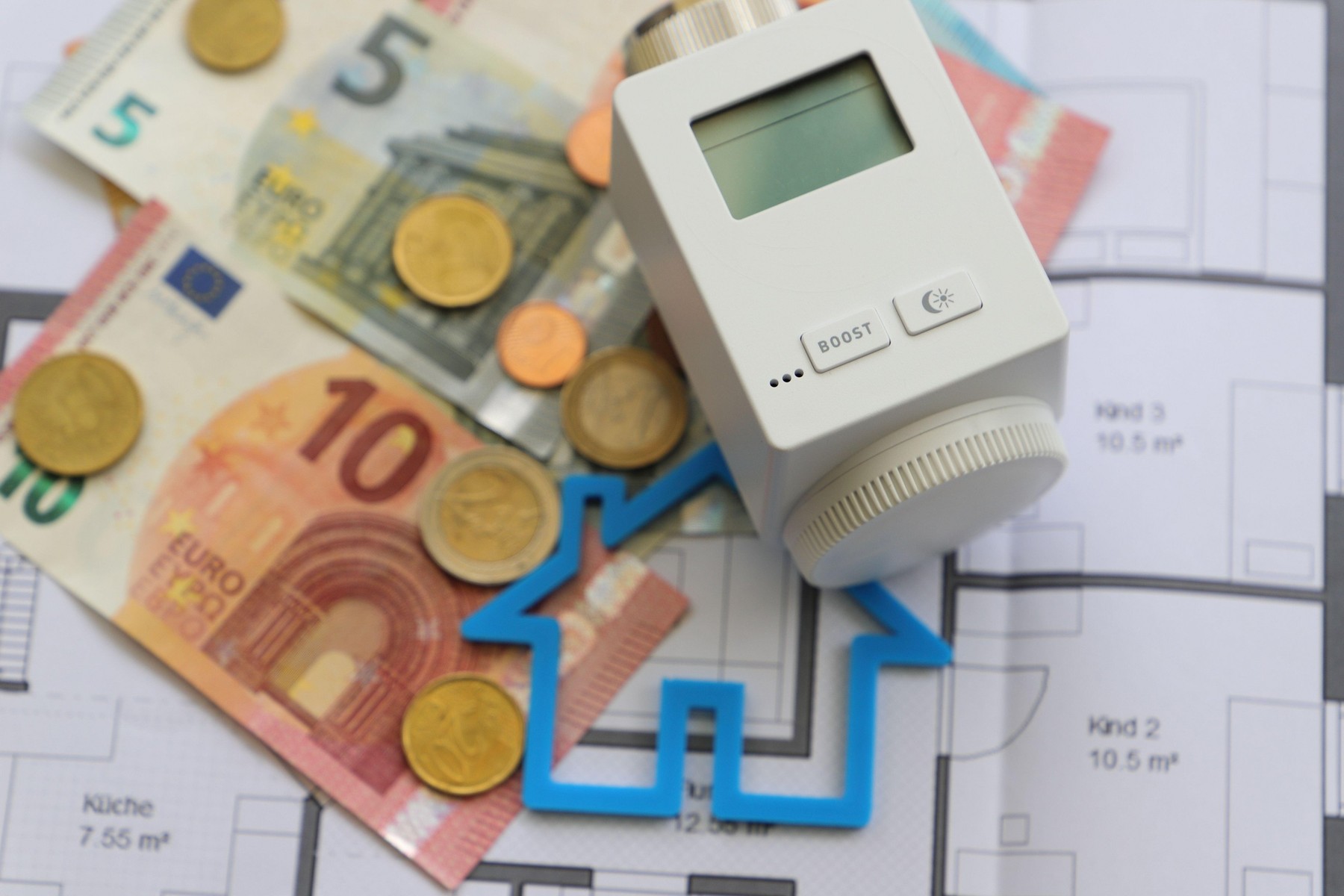 an electronic heating thermostat with money on a blueprint