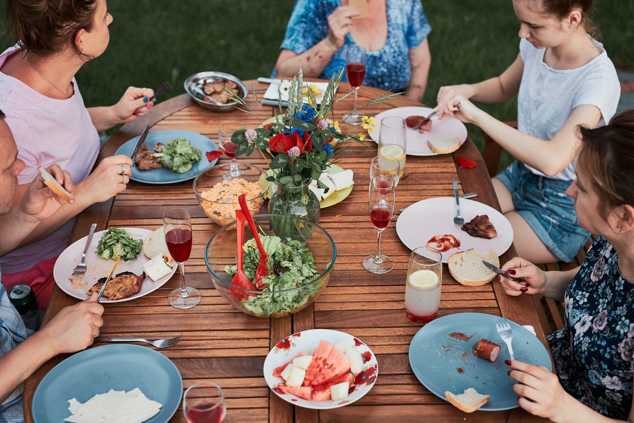 Family having a meal during summer picnic outdoor dinner in a ho