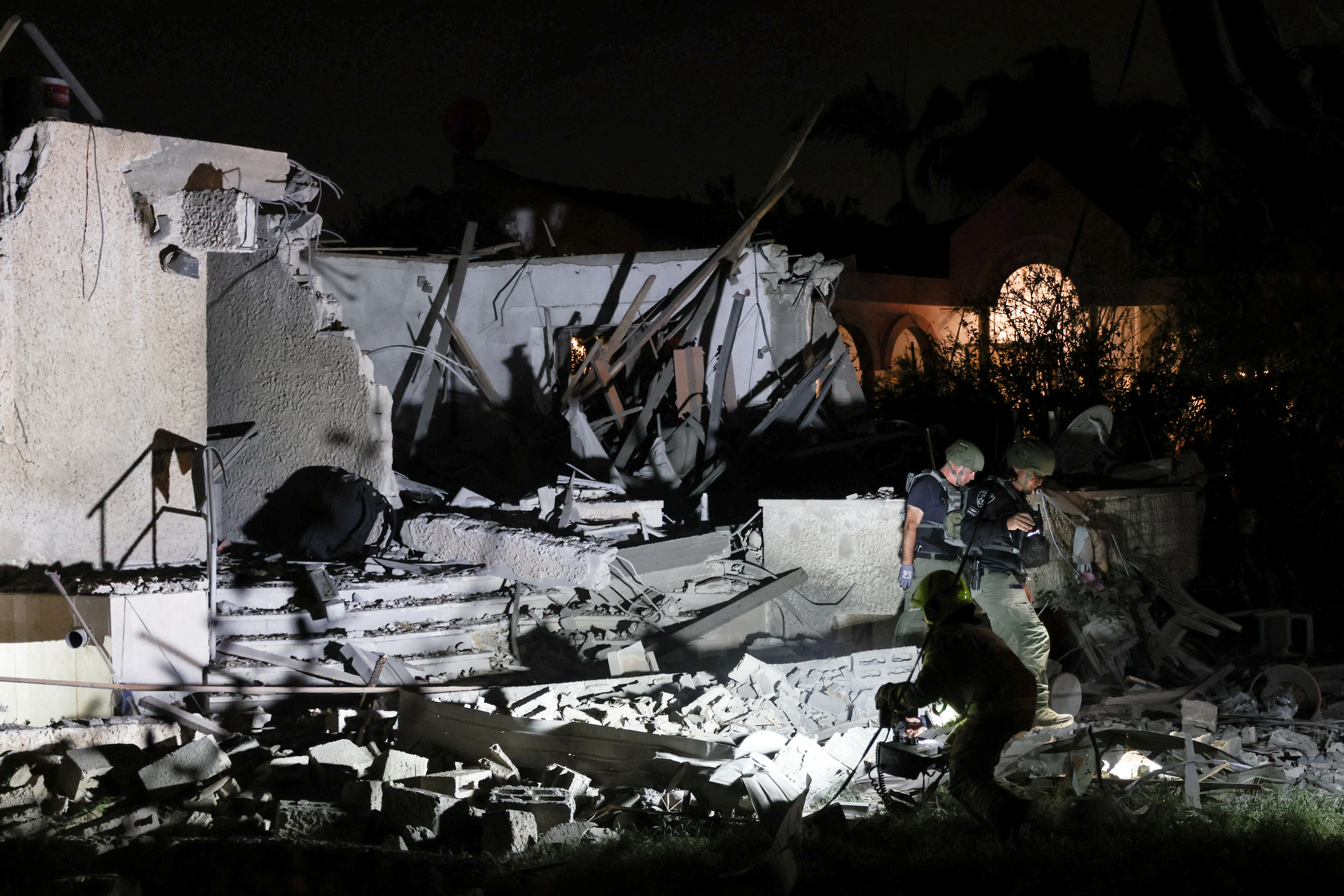 Israeli security officials work at the scene of a home that was struck and damaged by a rocket that was fired from the Gaza Strip towards central Israel