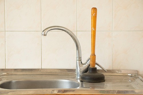 The plunger stands at the sink in the kitchen, cleaning clogged pipes, an old plunger for cleaning pipes