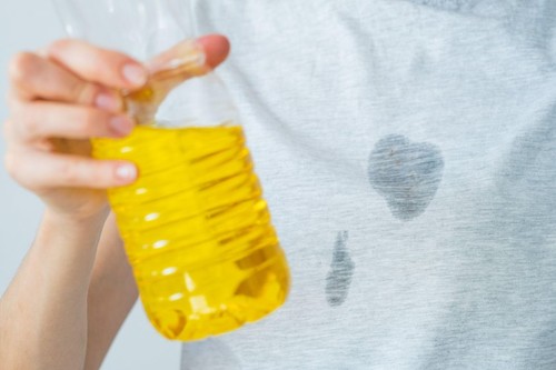 Grease stains in a clothes. An unrecognized woman is holding a corn oil. daily life stain concept