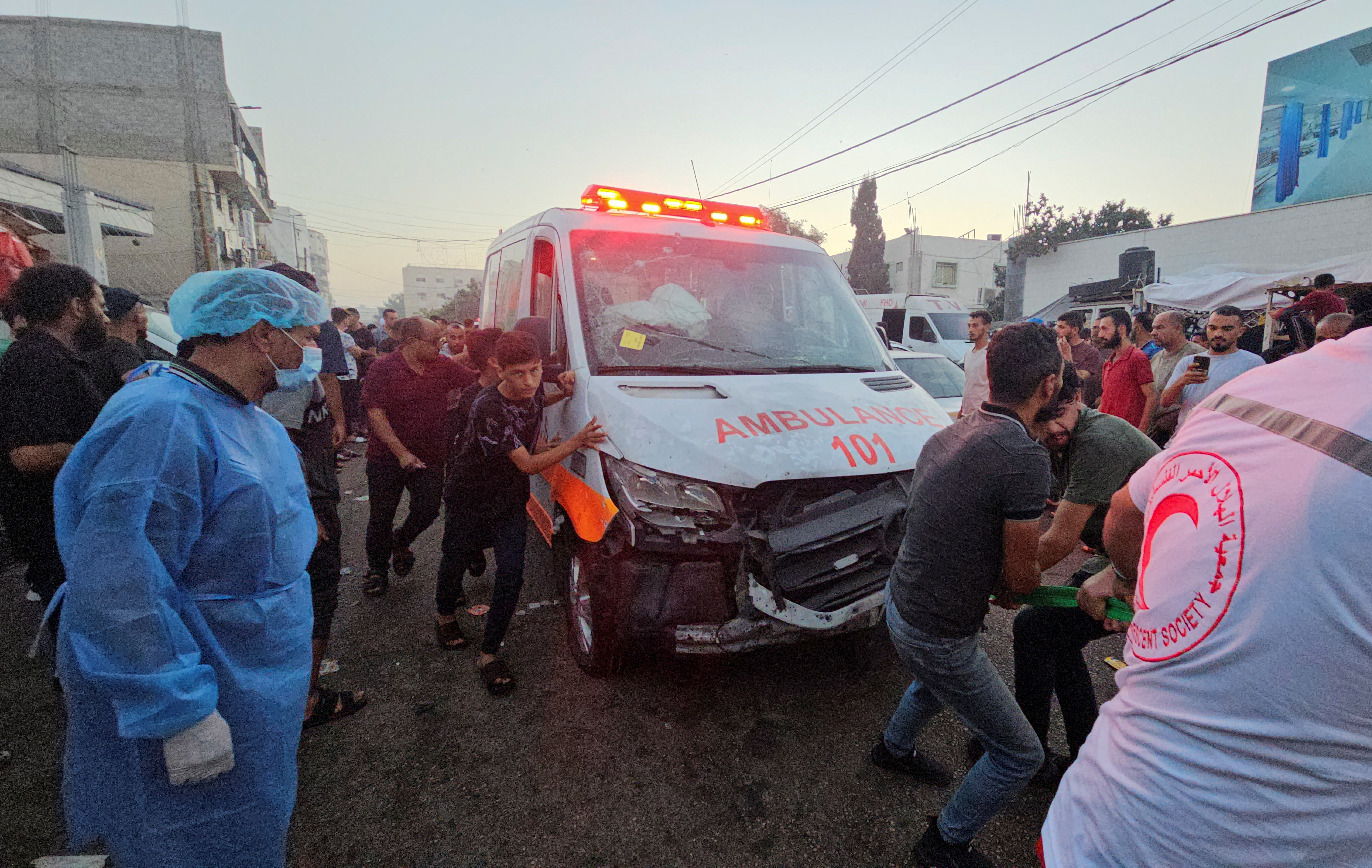 Palestinians check the damage of an ambulance convoy