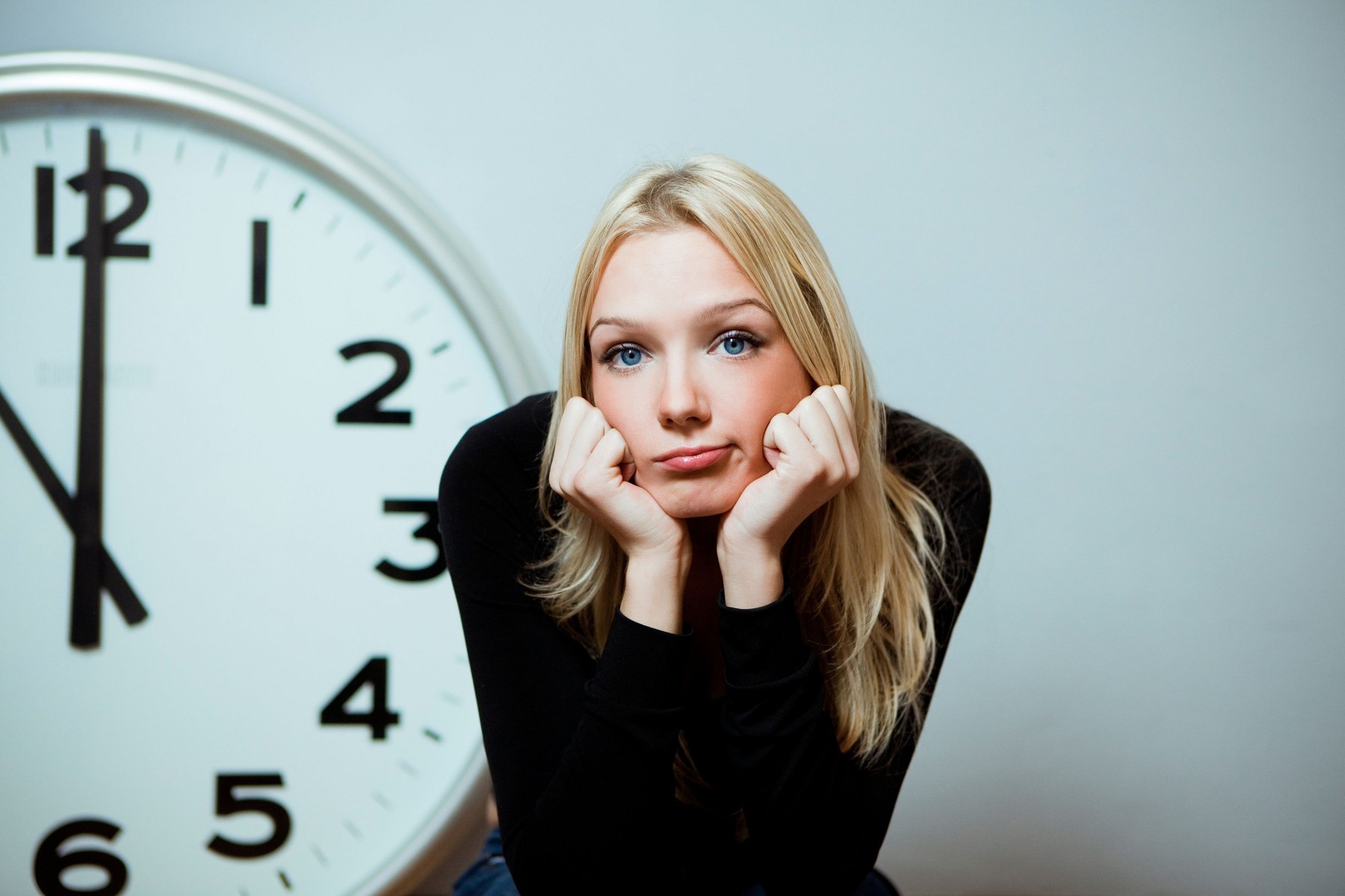 bored woman with a big clock on the wall