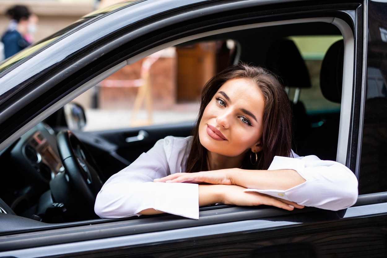 Smiling young brunette woman driving a car
