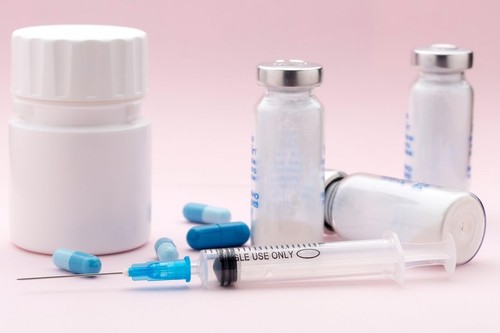 The set of medicine bottles, blue pills and injection syringe