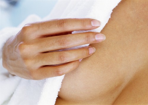 Woman covering breast with bathrobe, focus on hand and breast.