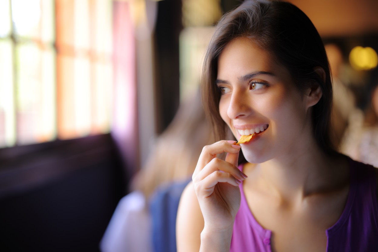 Happy woman eating chips in a restaurant interior