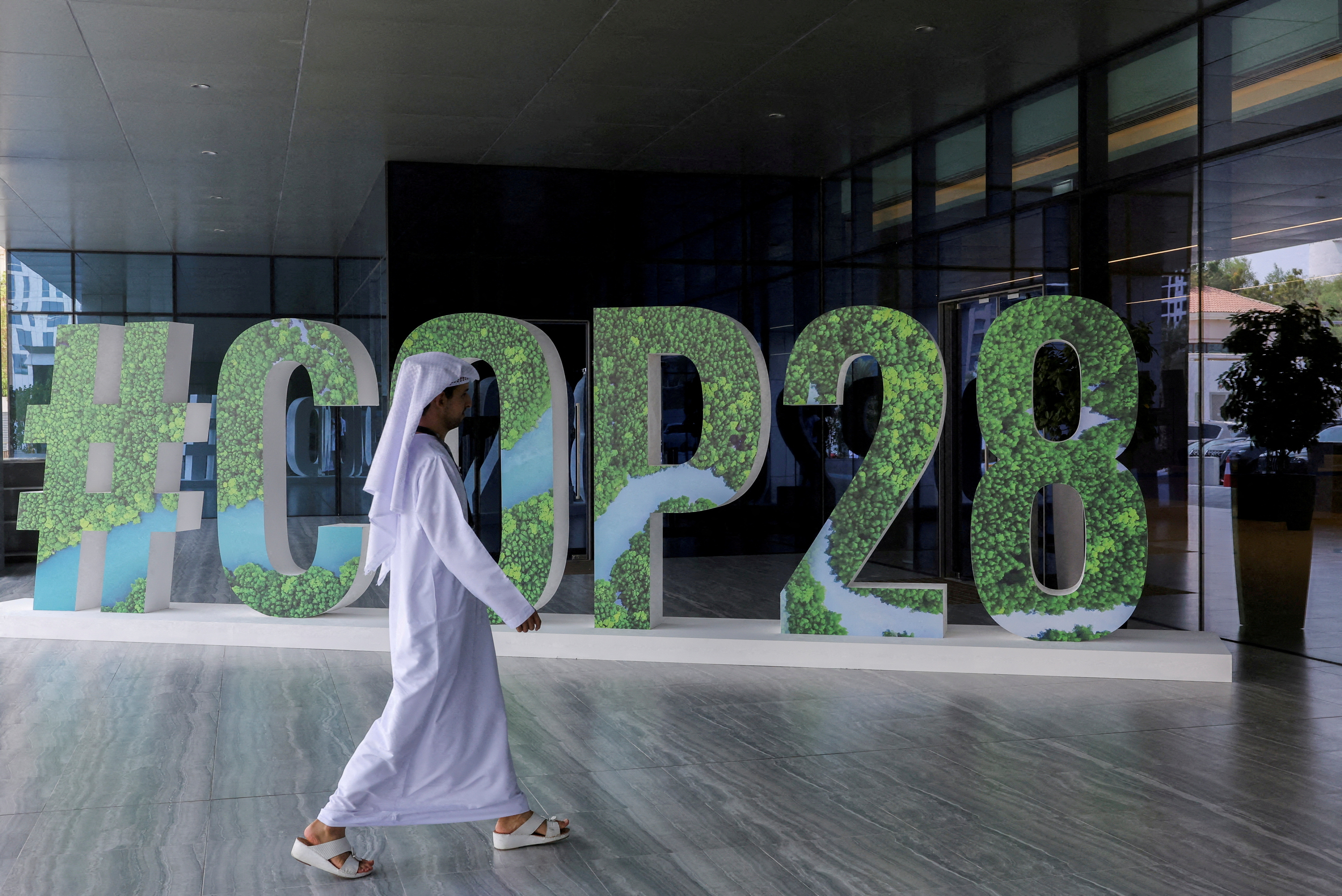 FILE PHOTO: A person walks past a "#COP28" sign during The Changemaker Majlis, a one-day CEO-level thought leadership workshop focused on climate action, in Abu Dhabi