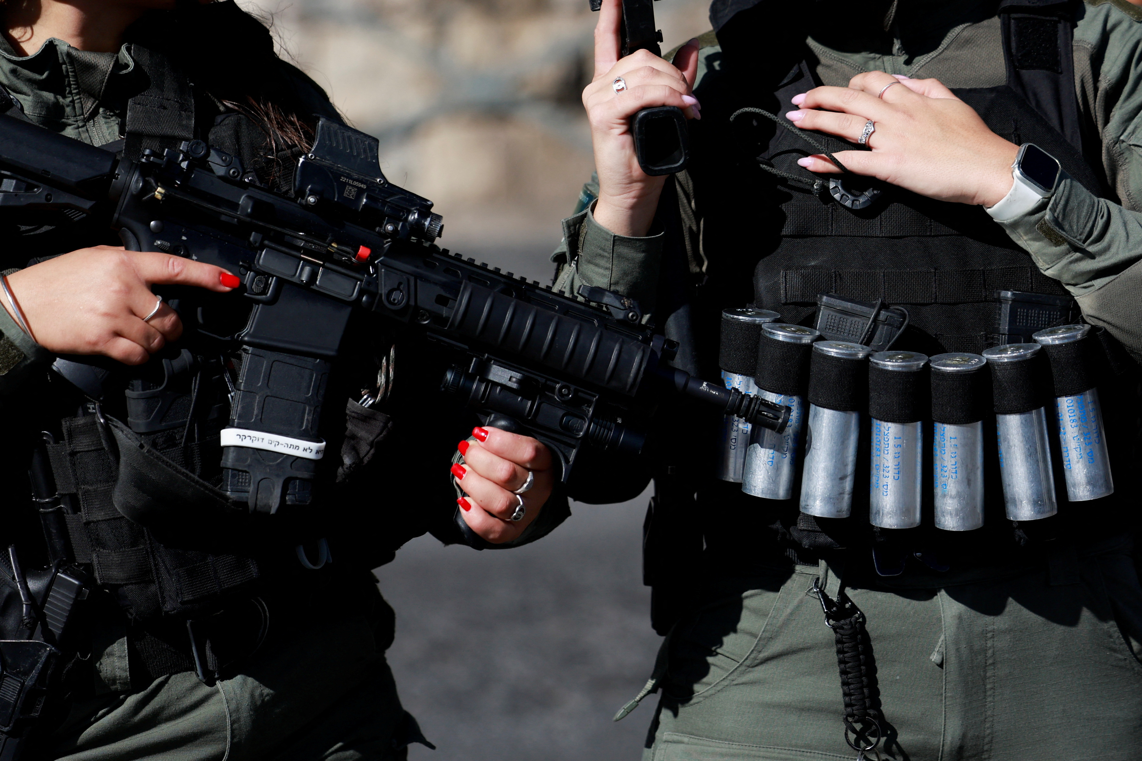An Israeli soldier holds a weapon as Muslim Palestinians hold Friday prayers, amid a temporary truce in Gaza between Hamas and Israel, in Jerusalem