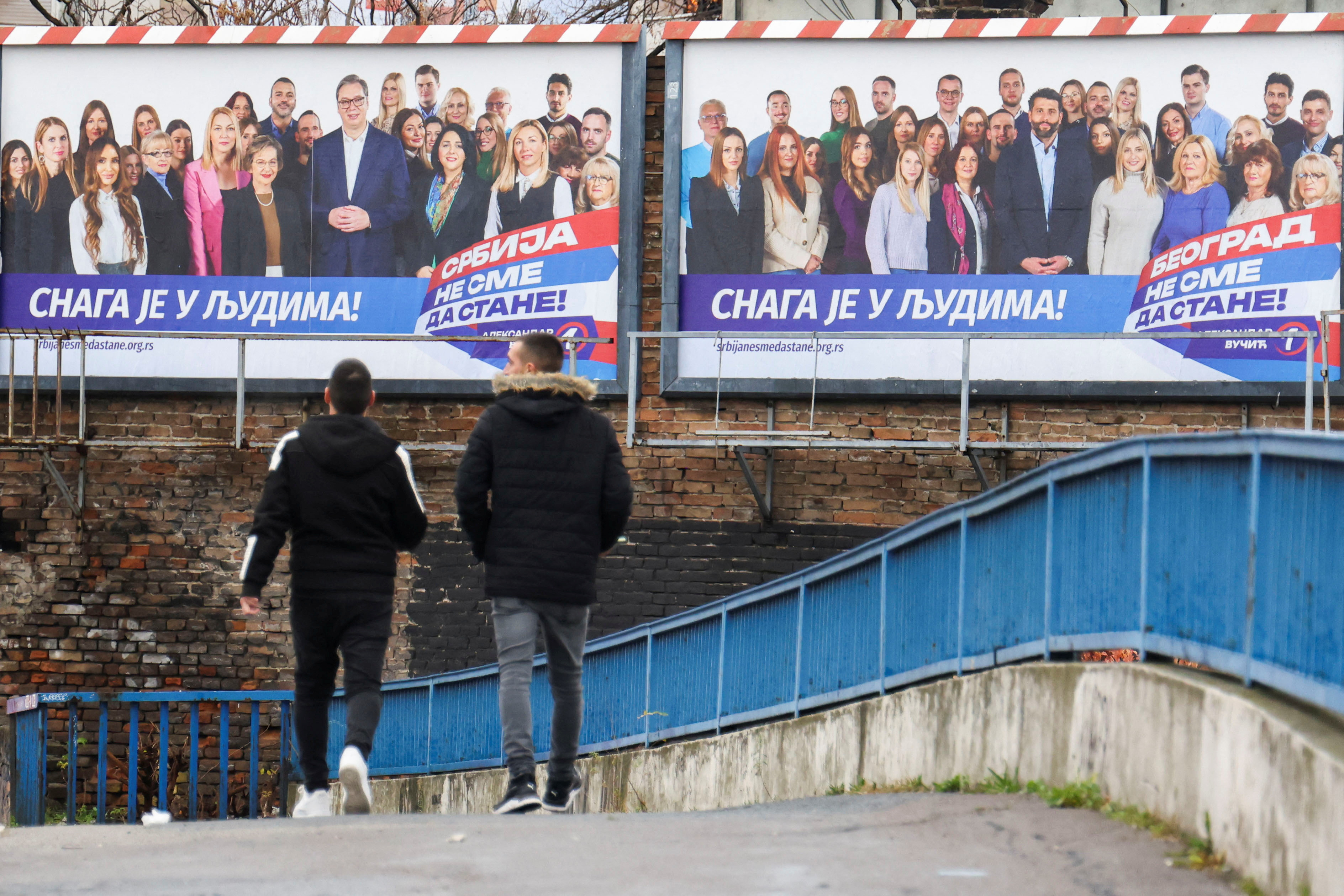 People walk next to a pre-election billboard of the Serbian Progressive Party in Belgrade