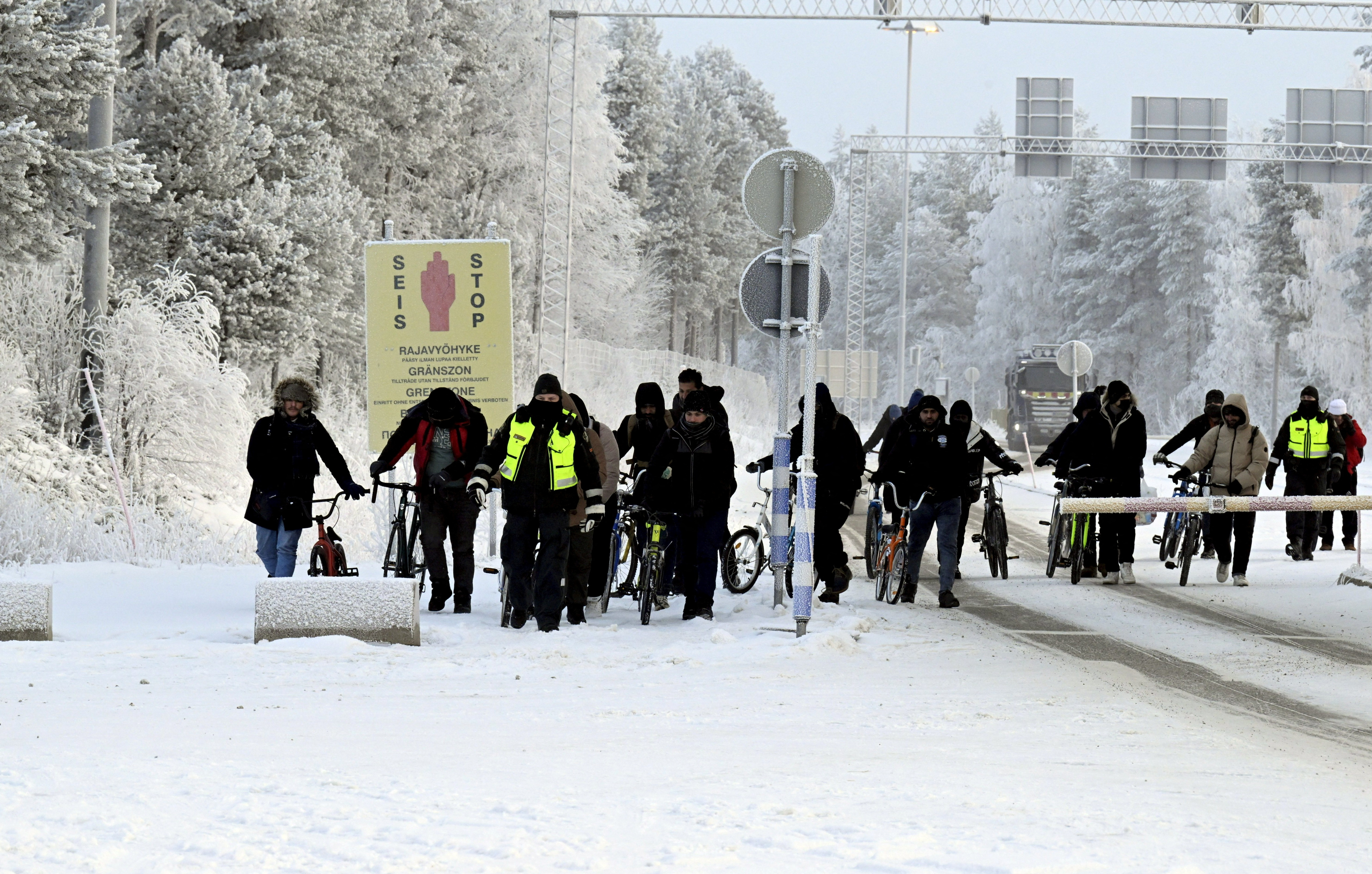 Migrants walk at the border crossing between Finland and Russia, in Finnish Lapland
