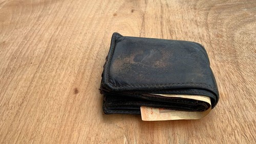 Old leather wallet on top of brown table.