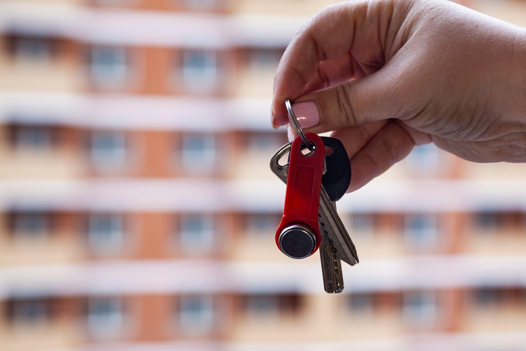 Keys in a hand on a background of an apartment building. Buying a property.