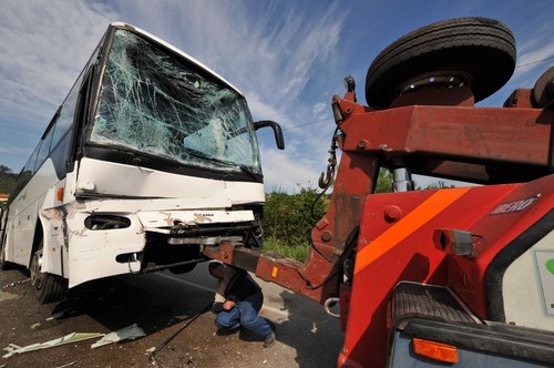 Man attaching a wrecked bus with shattered windscreen glass after a car crash to a tow truck