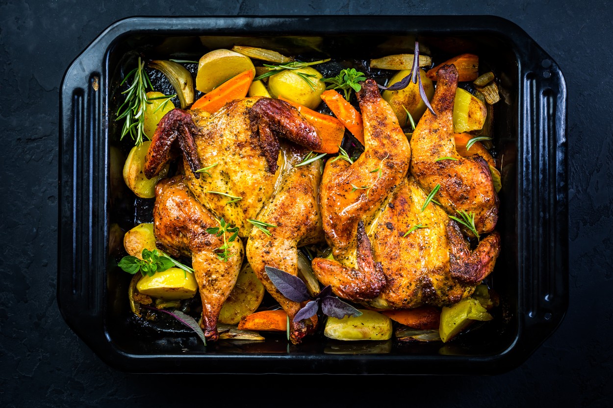Baked whole chicken with potatoes, carrots and herbs