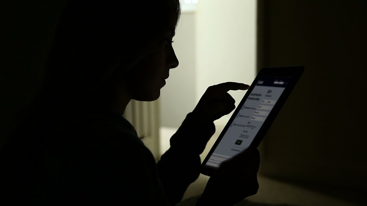Silhouette of a young girl using a digital tablet on Facebook page.