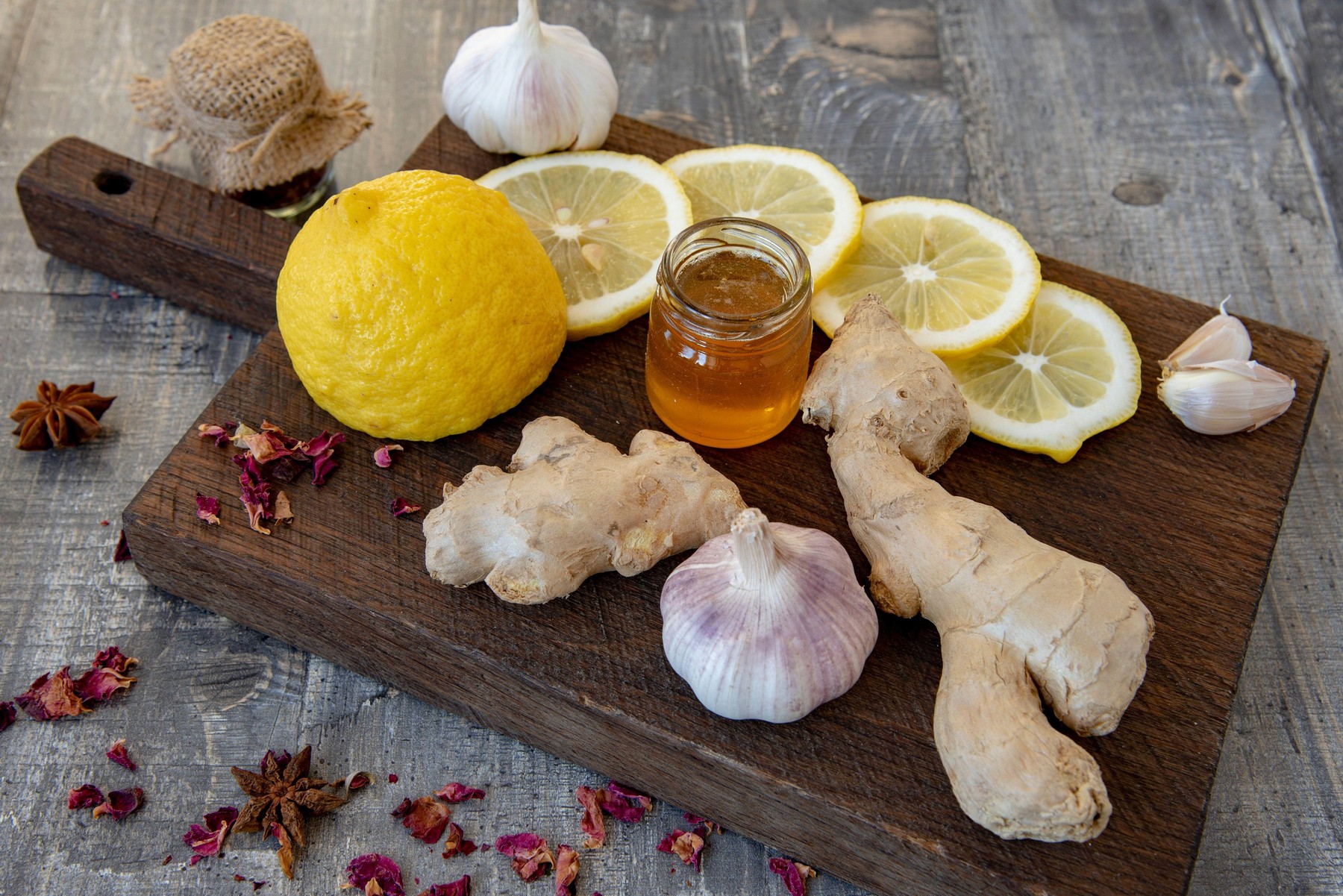 Garlic, lemon, honey, ginger and various spices on a rough wooden Board.