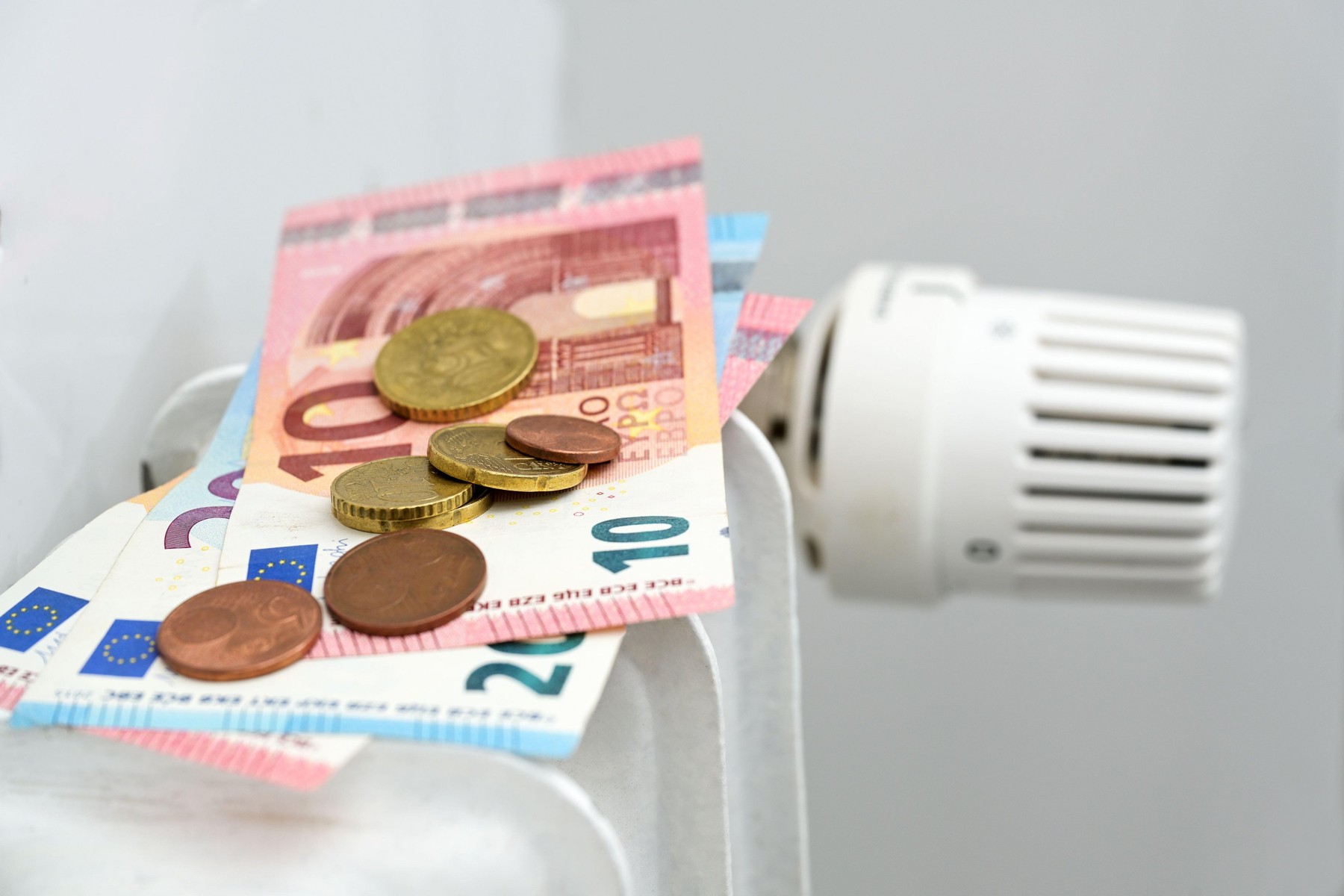 Euro banknotes and coins on a heating radiator, concept for rising energy prices and inflation, copy space, selected focus, narrow depth of field