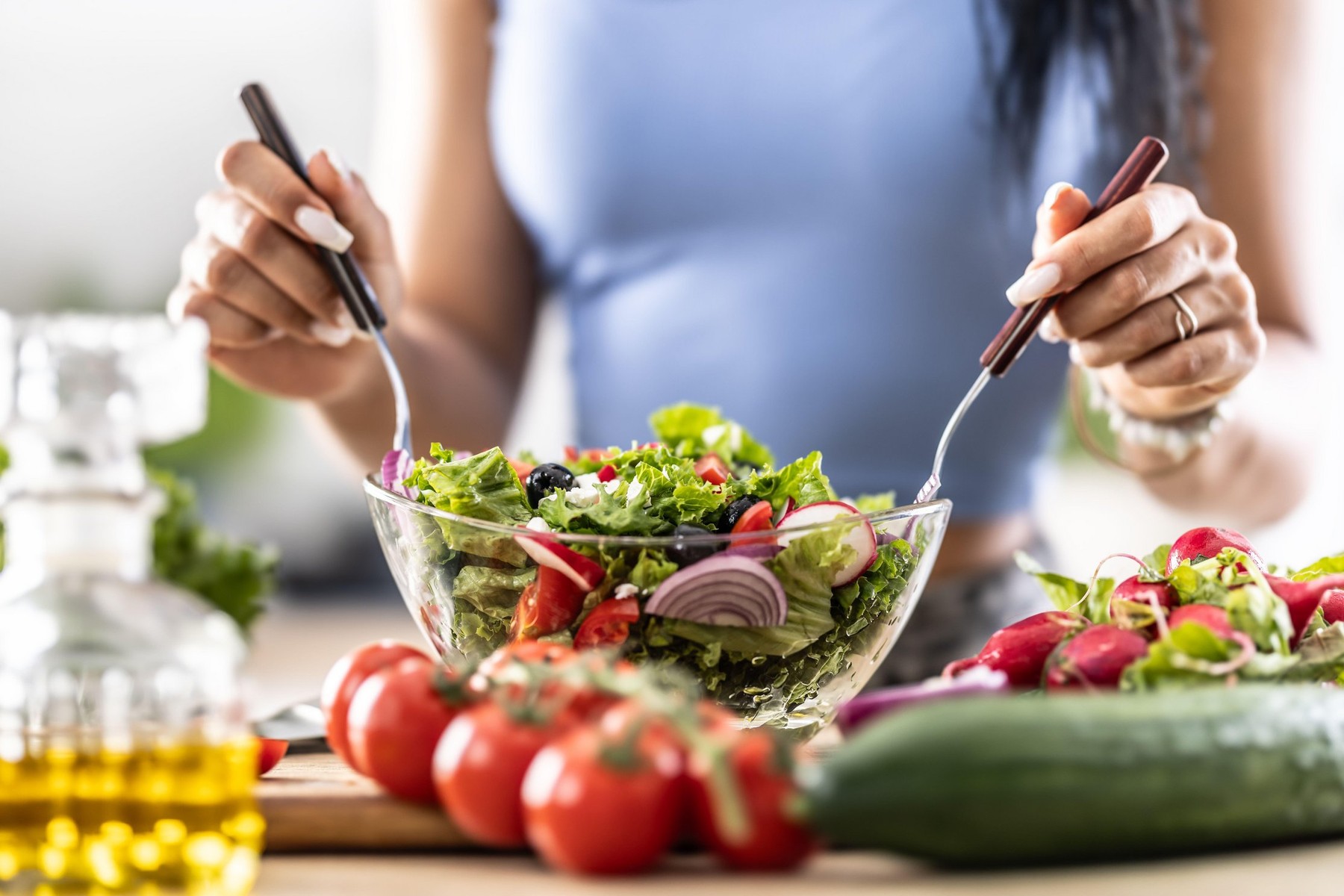 Female hands mixing a healthy spring salad made from various ingredients. Concept of healthy lifestyle.