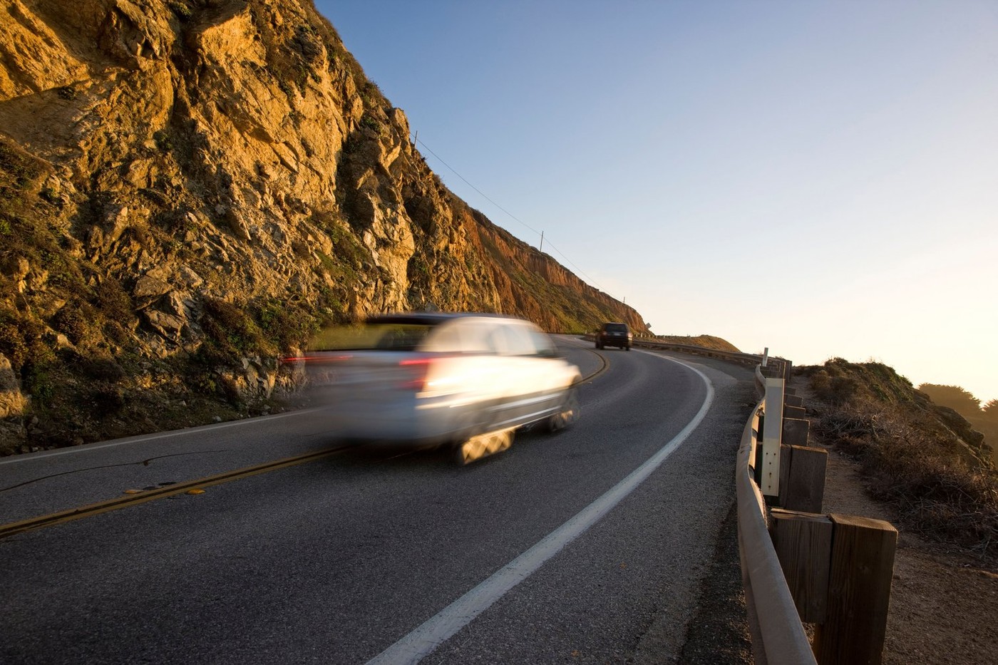 Speeding car in a blur of motion on highway 1 at sunset north of the Bixby Bridge, Big Sur, California, USA