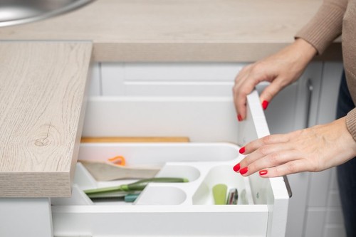 woman's hand opens a kitchen drawer with cutlery. female hand opens kitchen cabinet with utensils. drawer with kitchen utensils. close up