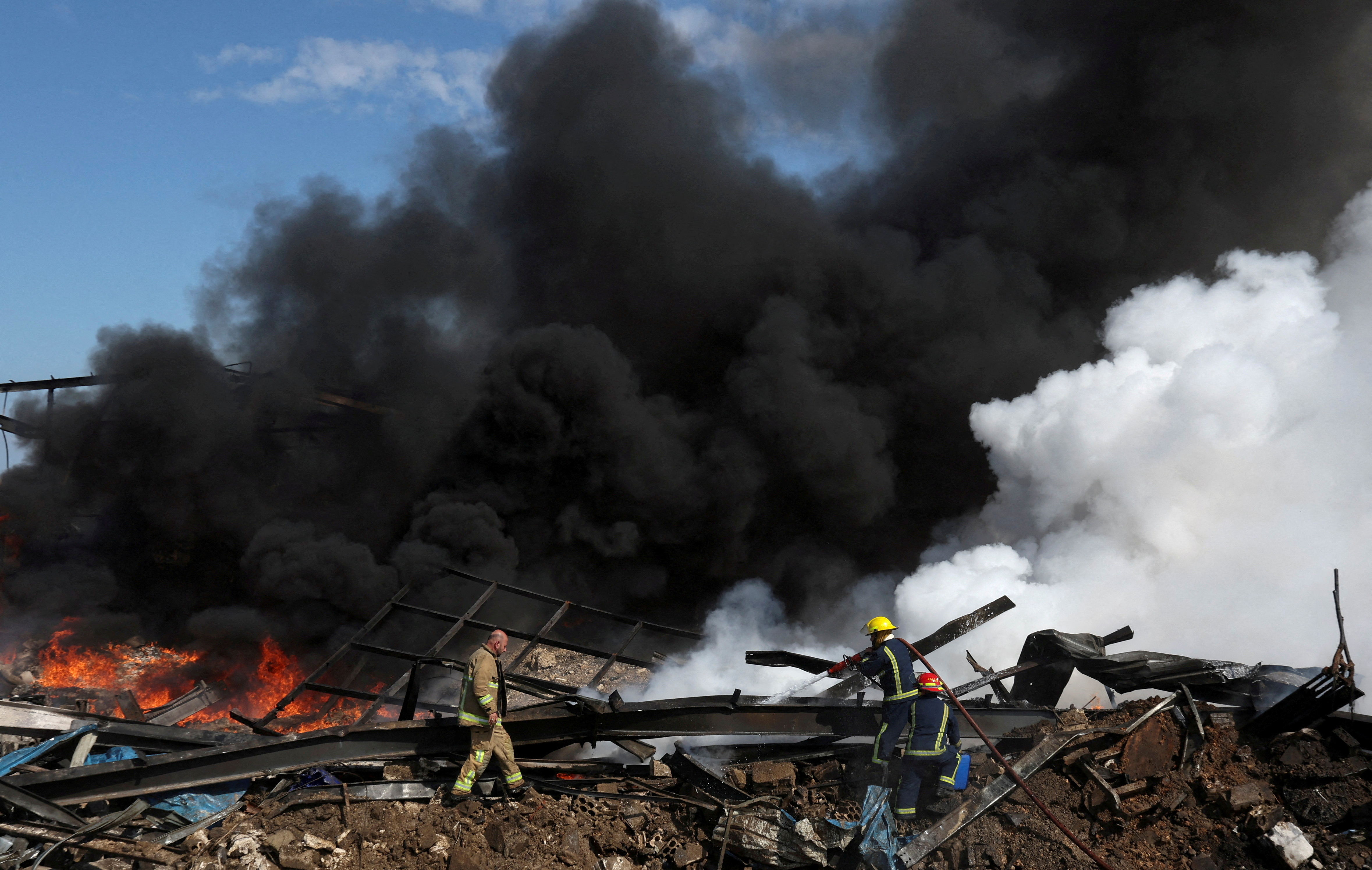 FILE PHOTO: Firefighters work as smoke billows at a site that was hit by an airstrike on Monday, near the town of Ghaziyeh