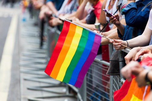 A spectator waves a gay rainbow flag at an LGBT gay pride march in London