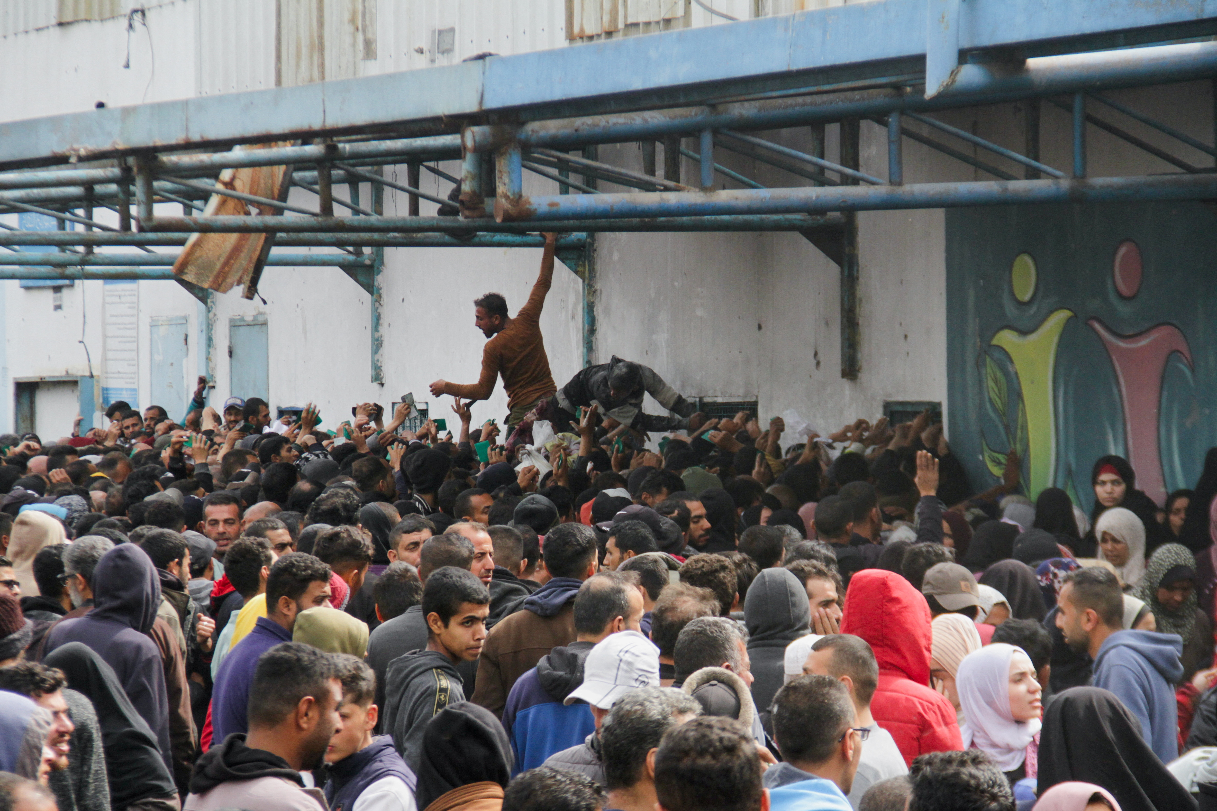 Palestinians gather to receive aid outside an UNRWA warehouse in Gaza City