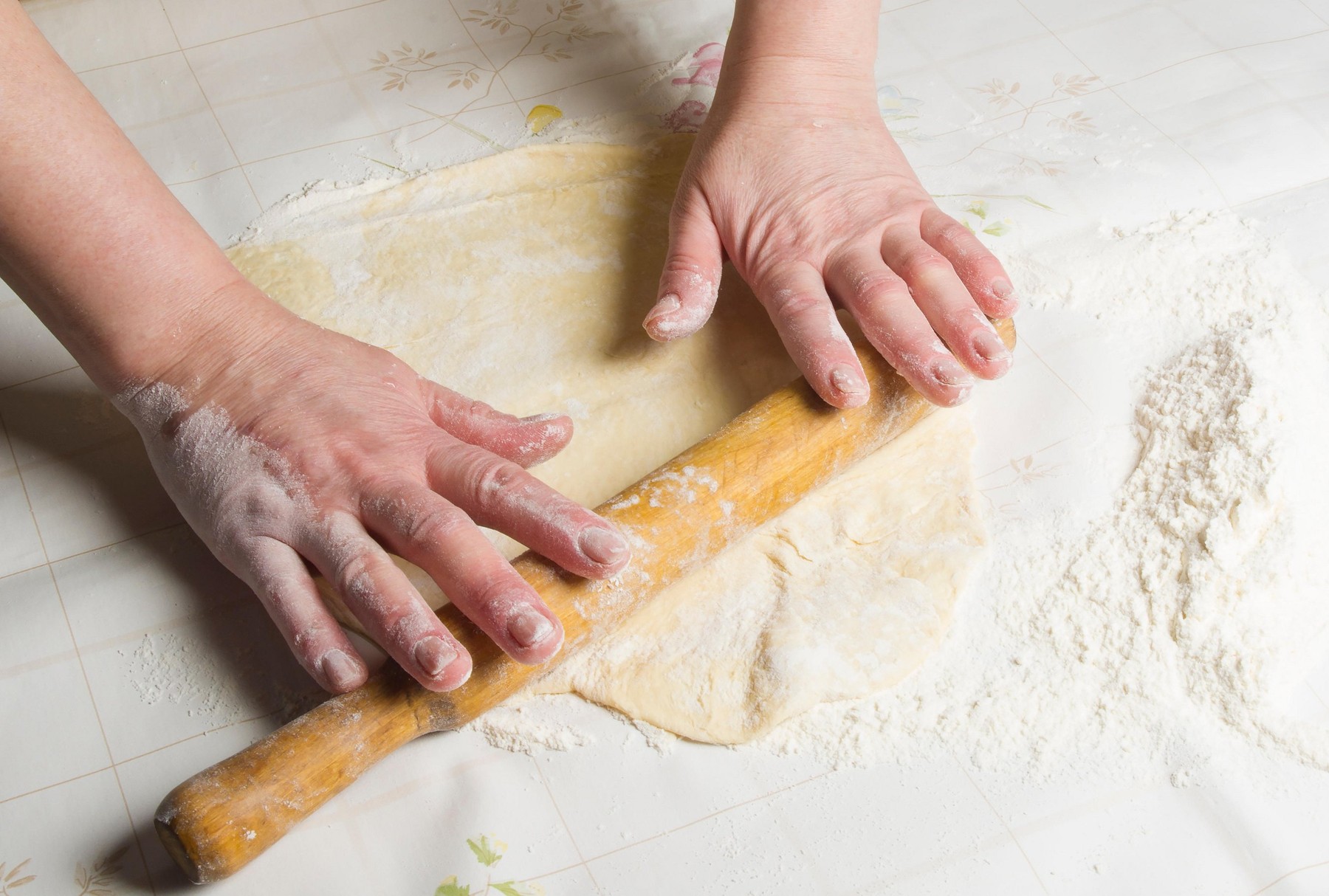 Making dough by female hands on white table background