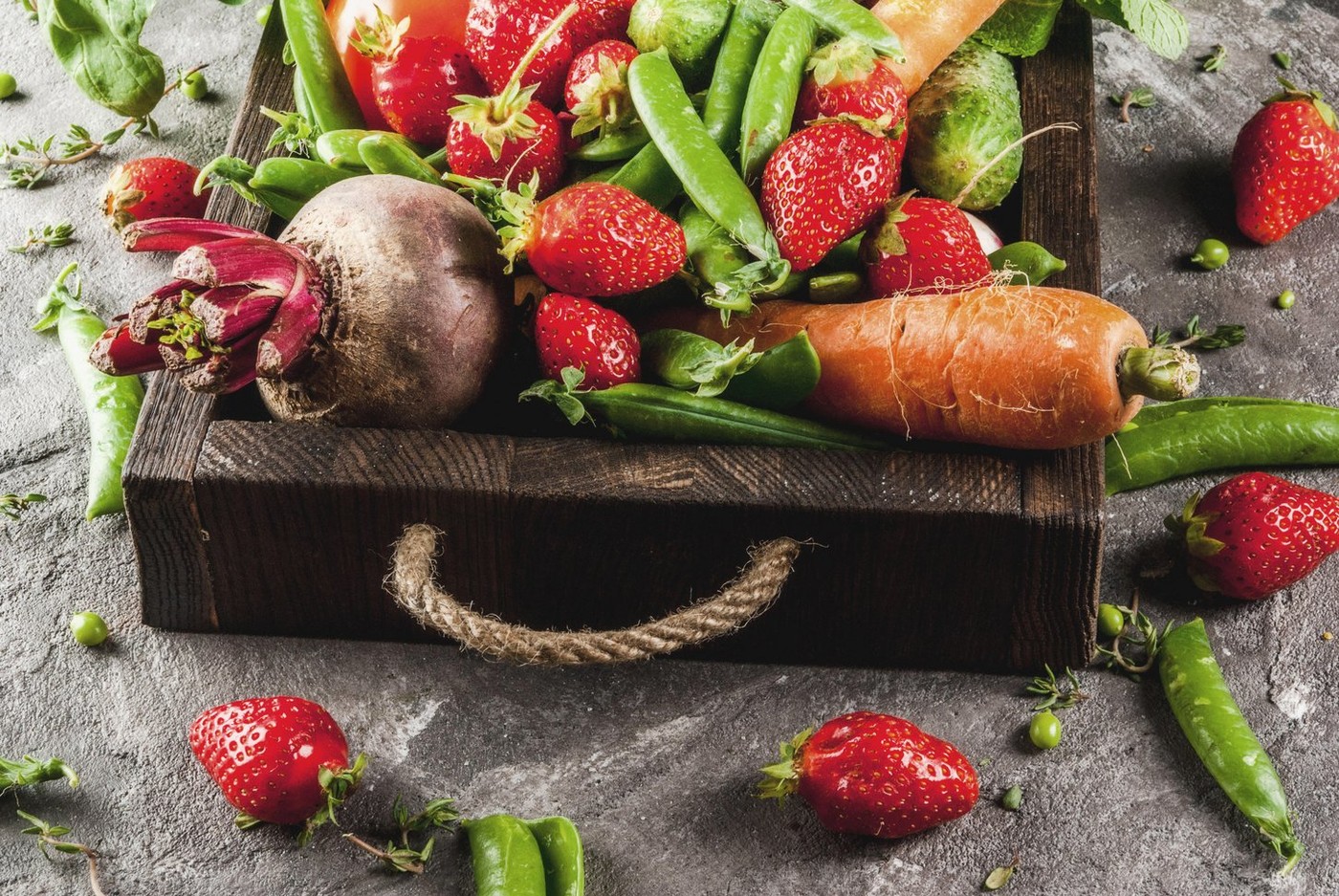 Market. Healthy vegan food. Fresh vegetables, berries, greens and fruits in wooden tray: spinach mint thyme strawberry carrots beets cucumbers radish
