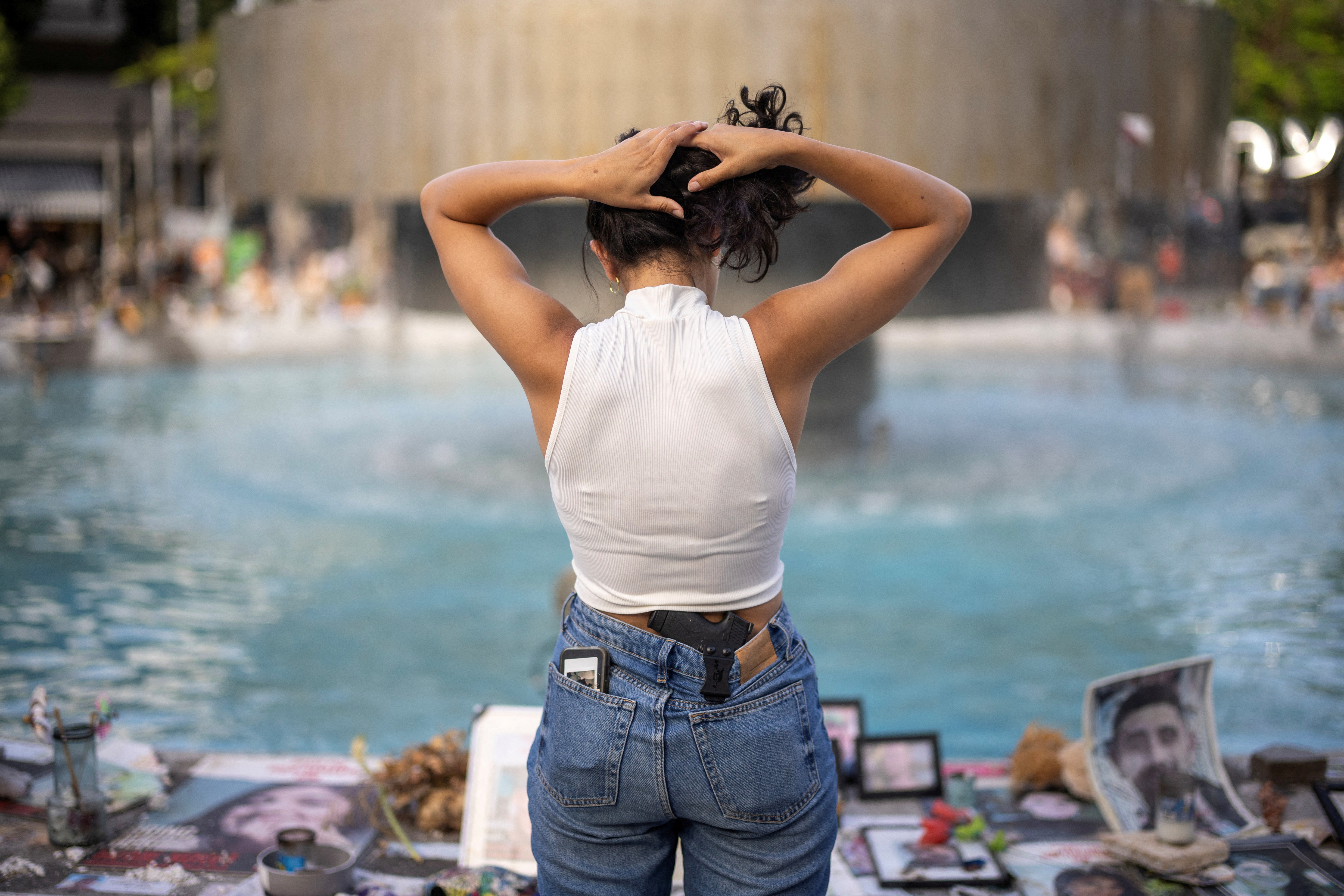 Woman stands next to pictures of hostages kidnapped during the deadly October 7 attack by the Palestinian Islamist group Hamas, in Tel Aviv