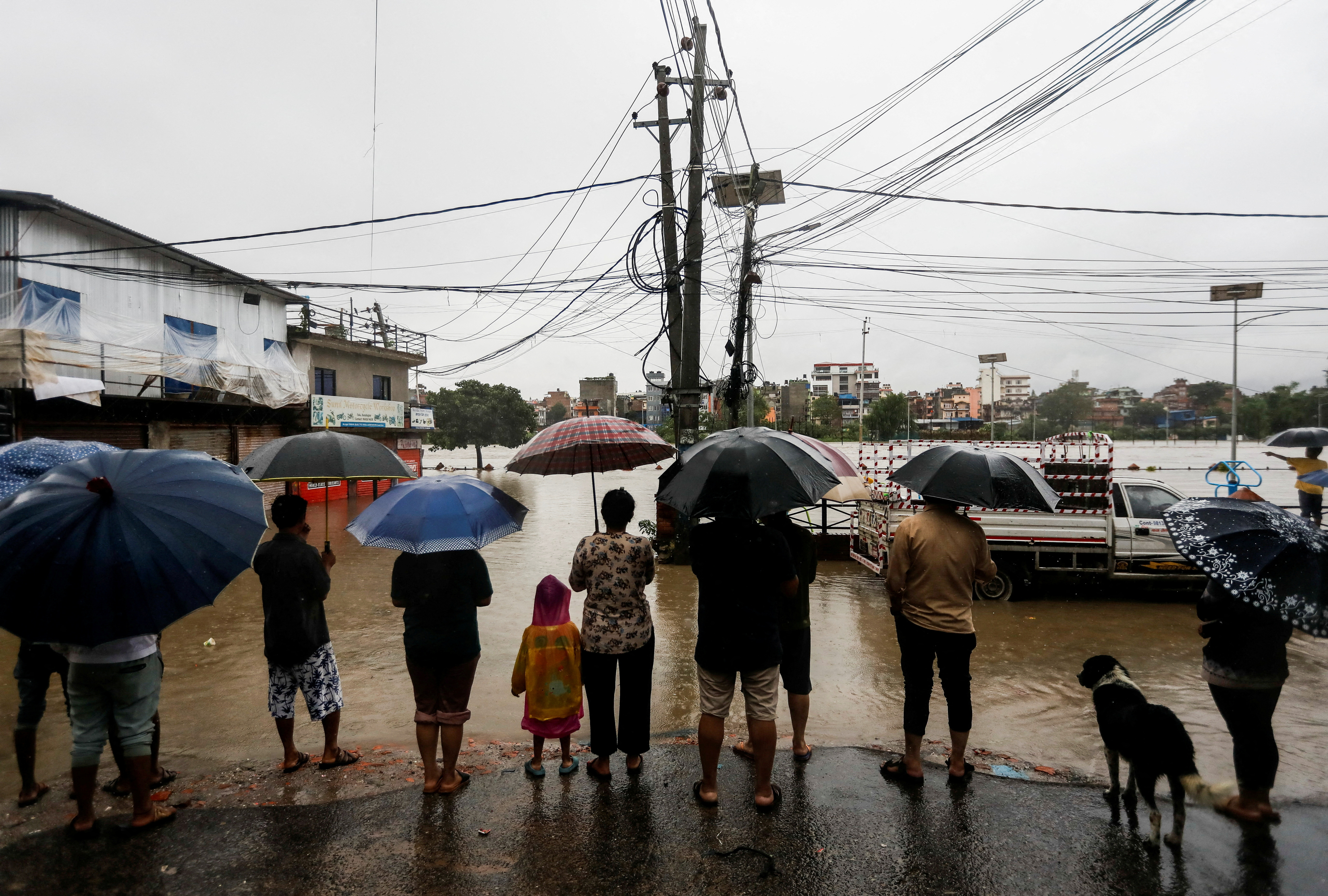 People look towards a flooded area along the bank of overflowing Bagmati River following heavy rains in Kathmandu