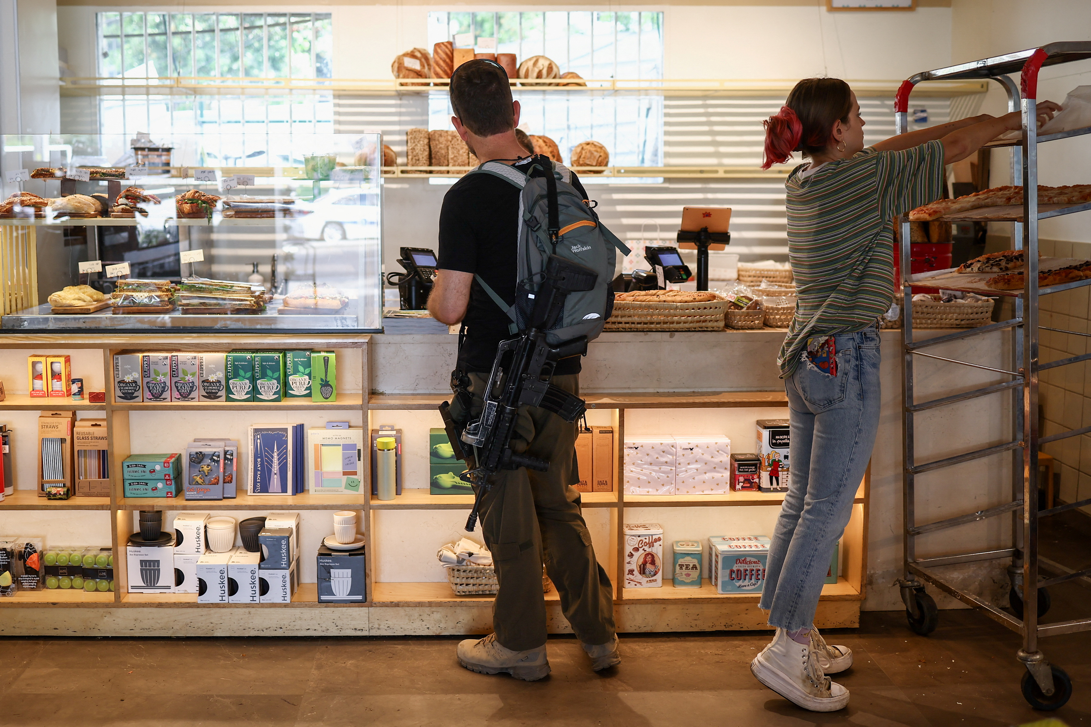 Israeli reservist carrying rifle orders at coffee shop in Tel Aviv