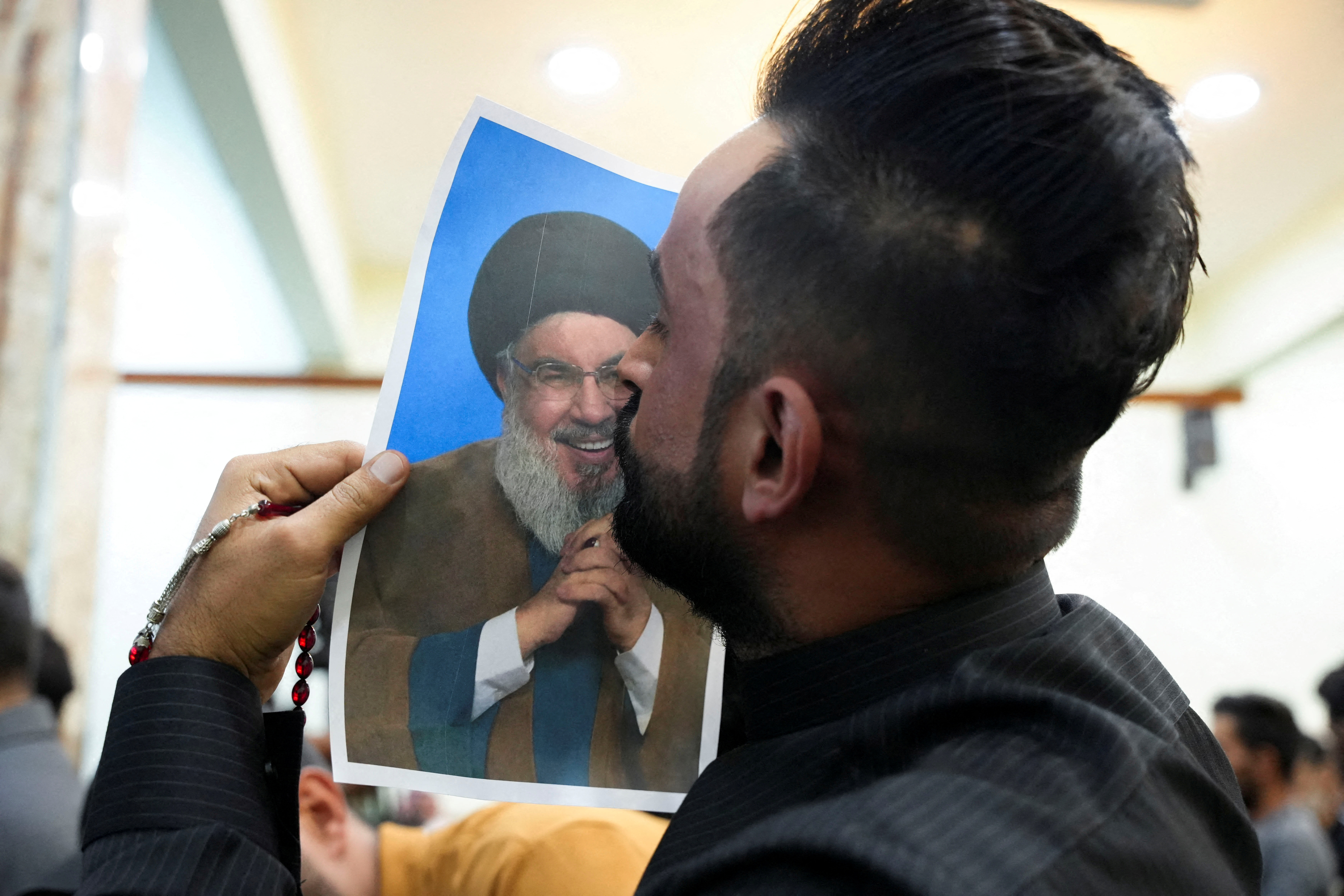 An Iraqi volunteer kisses a picture of Lebanon's Hezbollah leader Sayyed Hassan Nasrallah while registering his name to support Hezbollah, in Basra