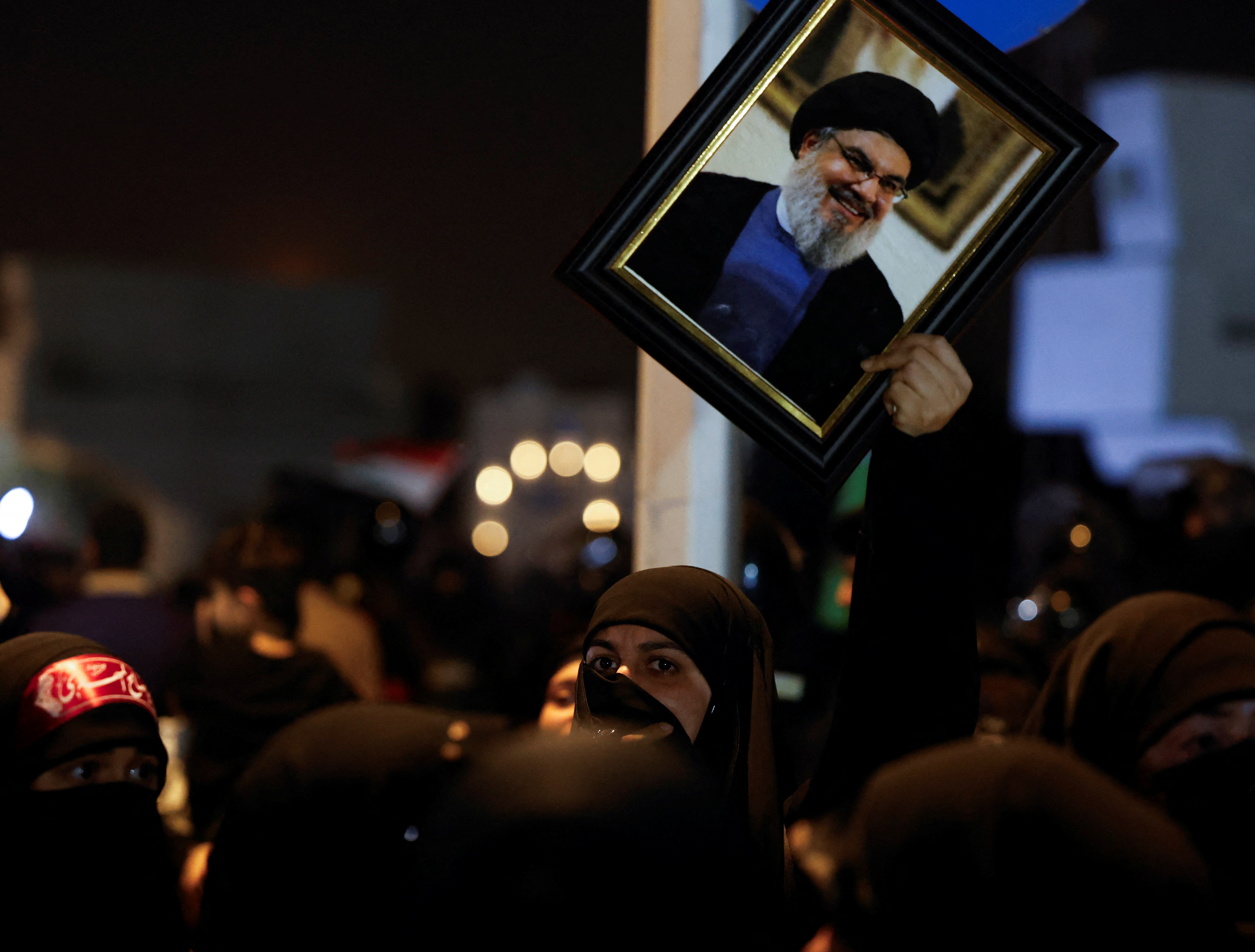 An Iraqi woman holds a picture of Lebanon's Hezbollah leader Sayyed Hassan Nasrallah as she attends a protest following the announcement of his death, in Baghdad