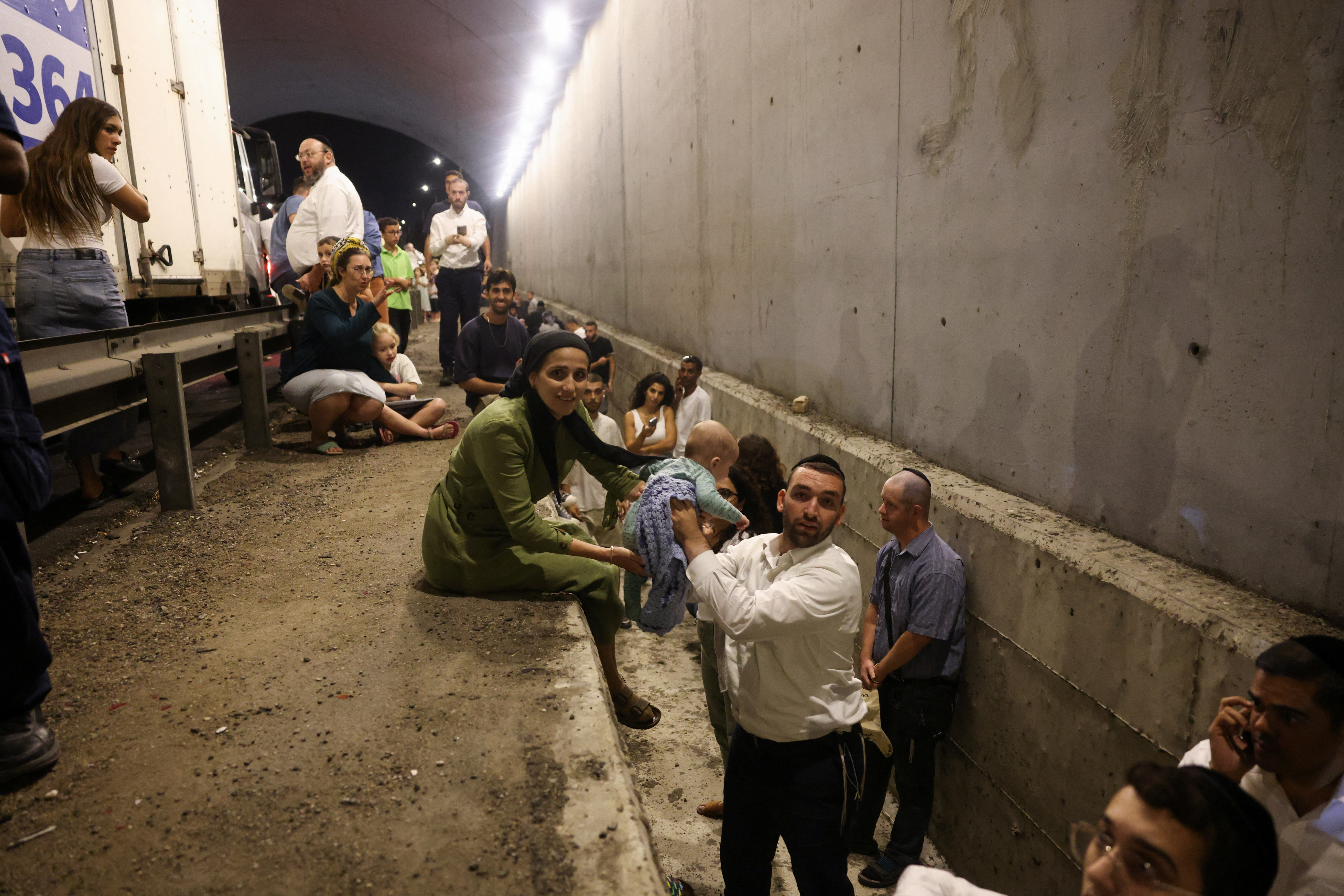 People take shelter during an air raid siren, in central Israel
