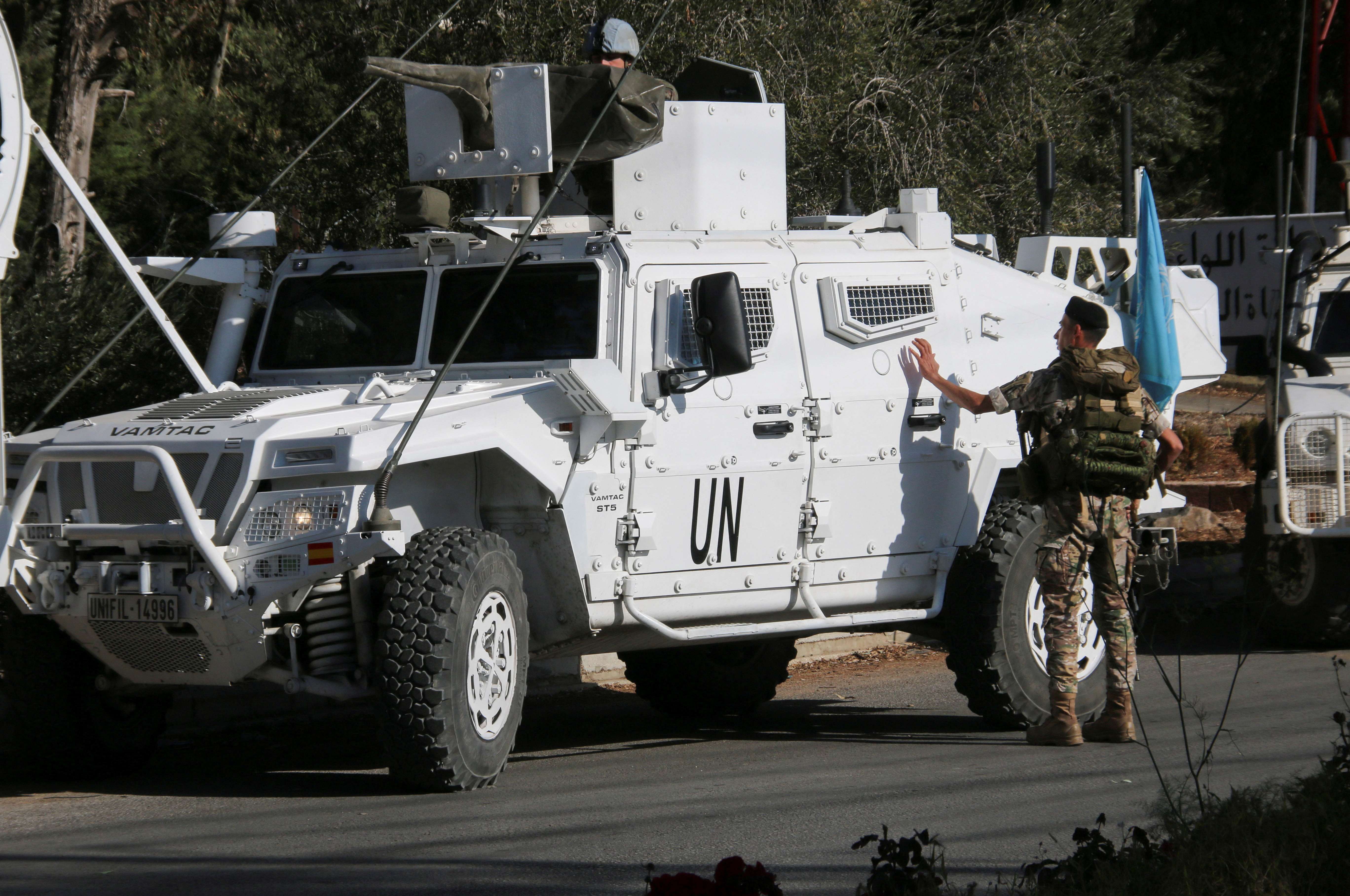 Lebanese army soldier stands near UN peacekeepers (UNIFIL) vehicles in Marjayoun