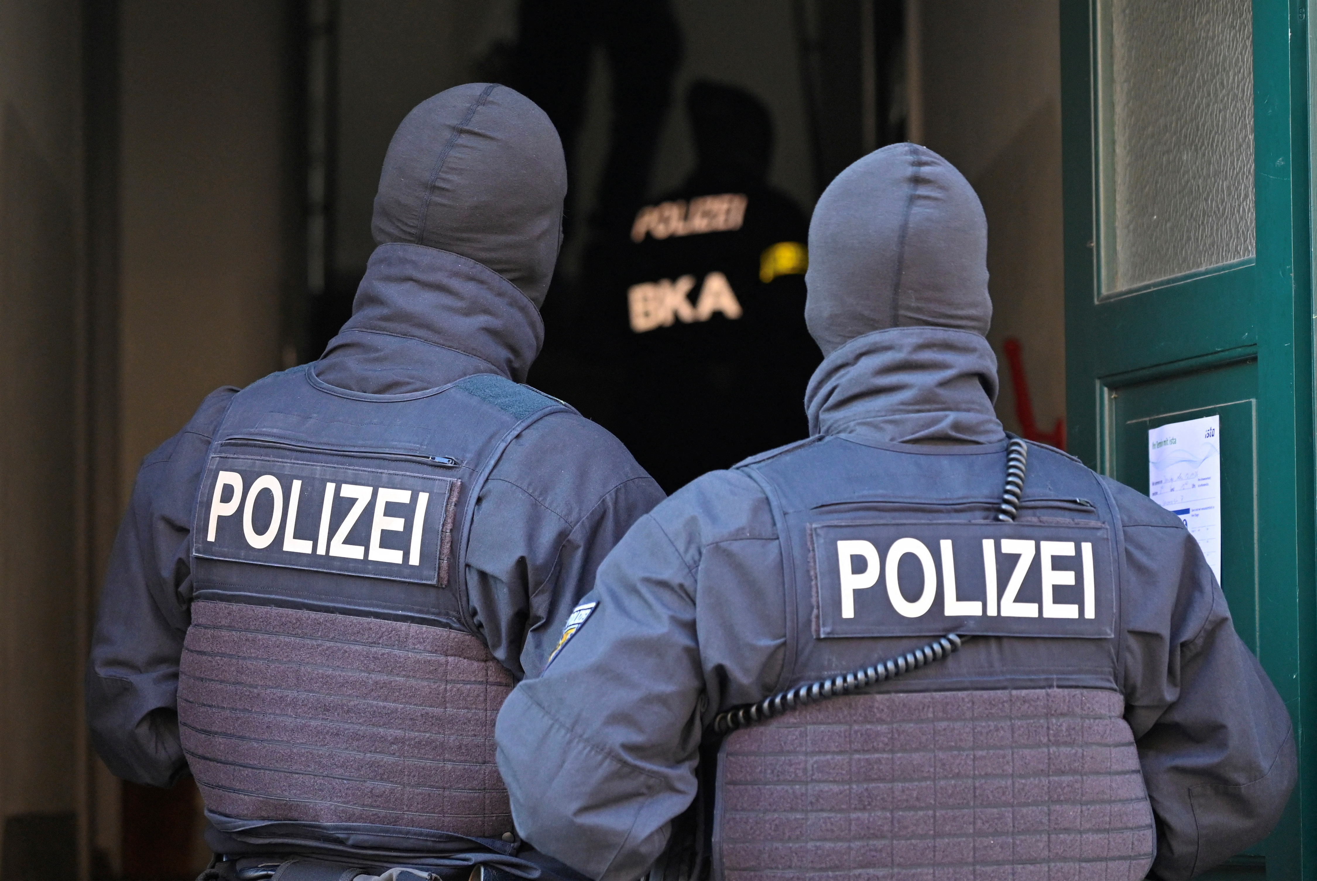 Masked German police officers guard a house in Dresden